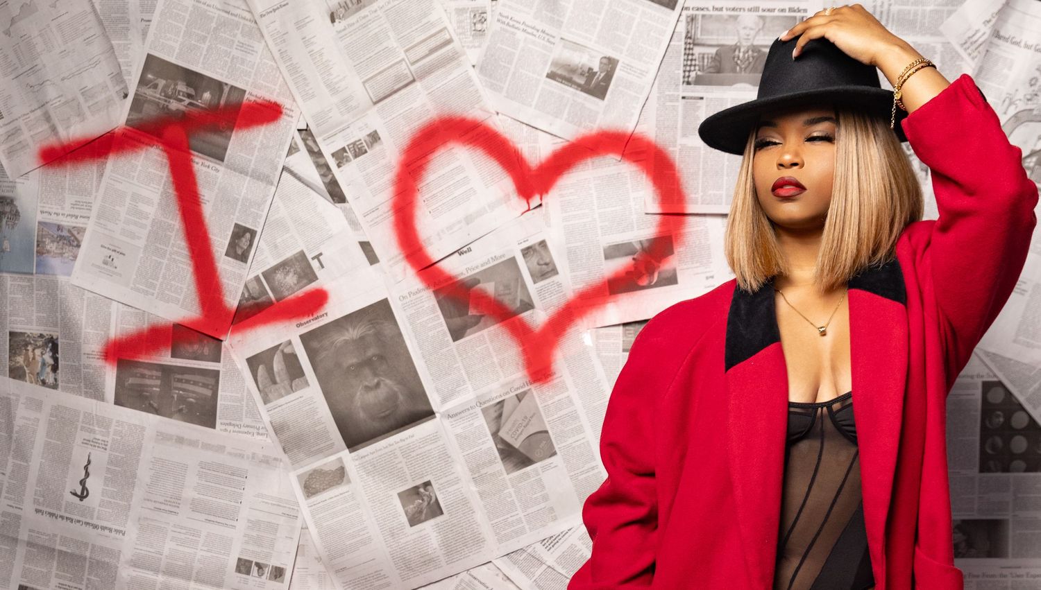 Stylish scene with red coat against newspaper wall featuring drawn heart graffiti.