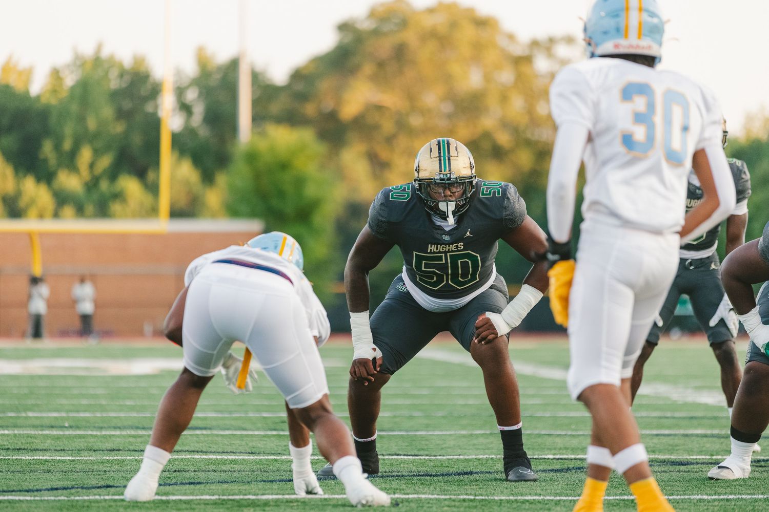 Football players from opposing teams face off at the line of scrimmage during a game.