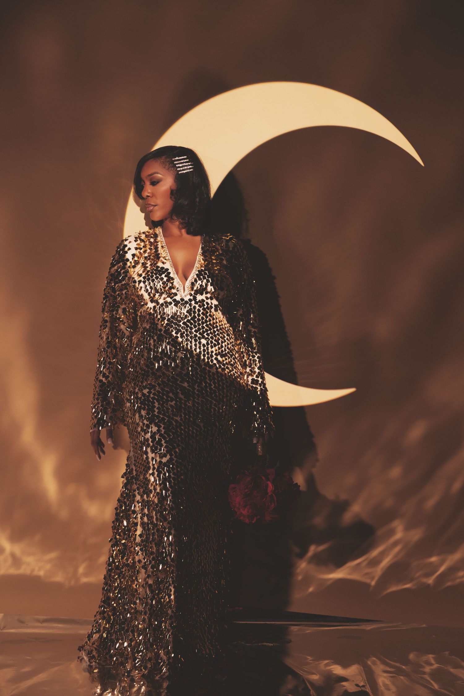 Ethereal fashion portrait with sequined gown against dramatic moon backdrop and moody lighting.
