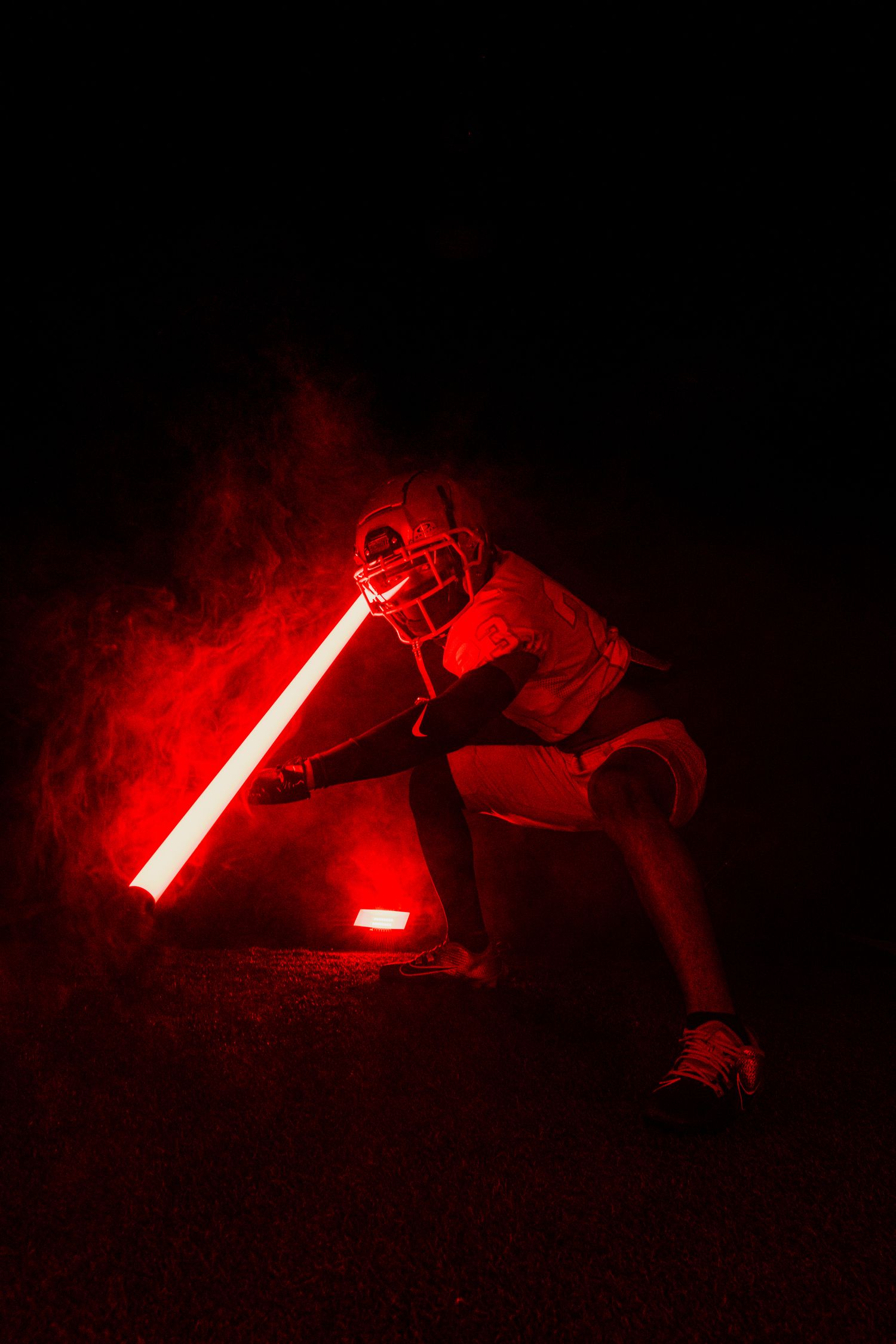 Dramatic silhouette of a person holding a glowing red lightsaber in dark atmosphere.