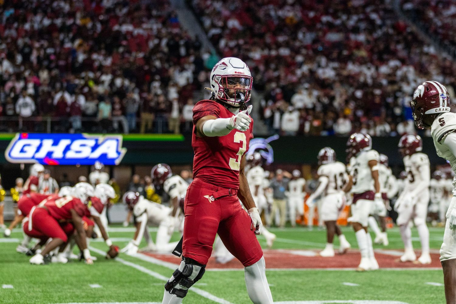 Football player in red uniform celebrating during a game in a packed stadium.
