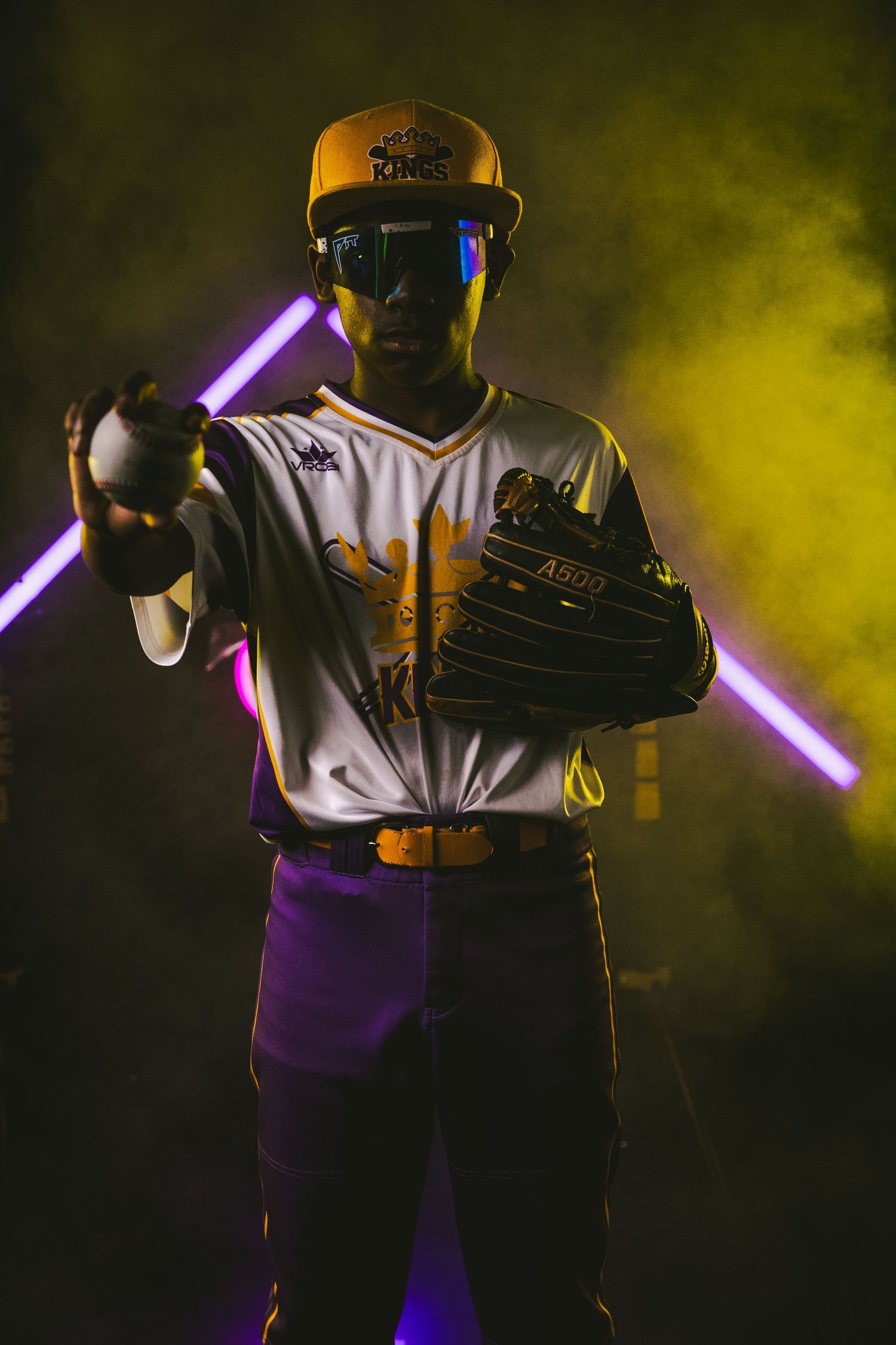 Baseball player poses with light-up neon tubes against dramatic yellow smoke background.