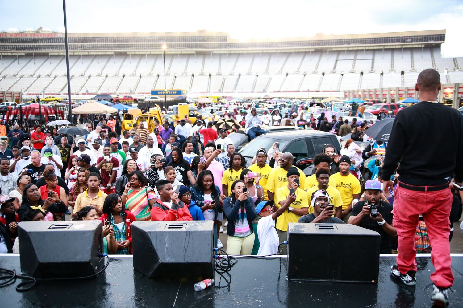 Large crowd gathers in front of outdoor stage setup with speakers and equipment for Juelz Santana concert