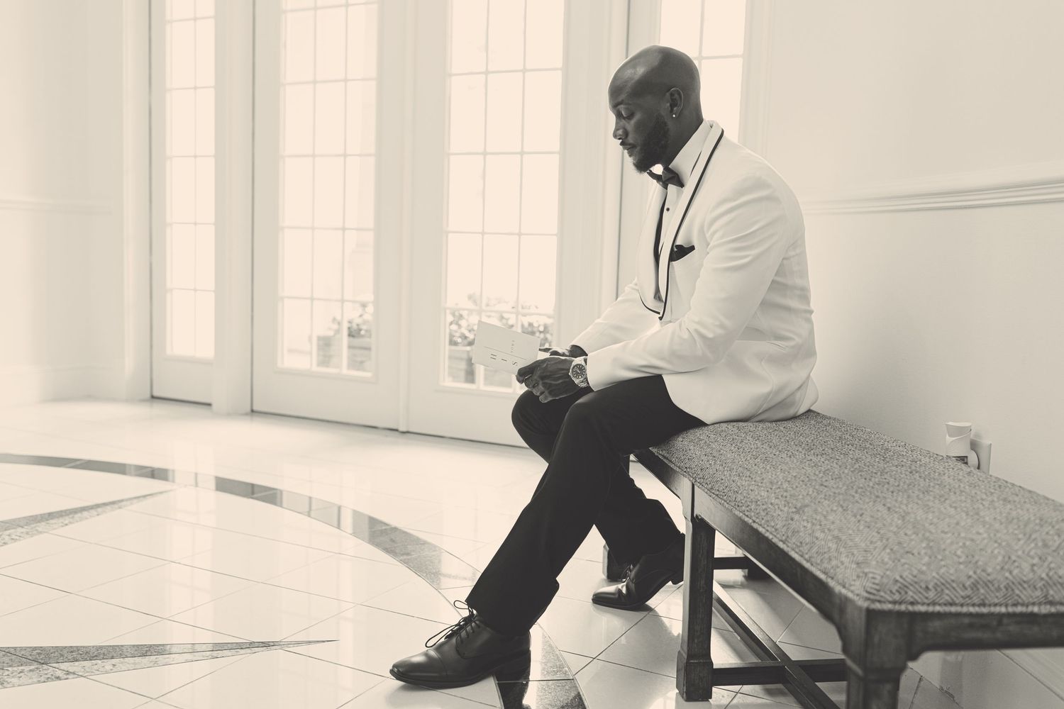 A vintage black and white photo of a person sitting alone on a bench in contemplation.