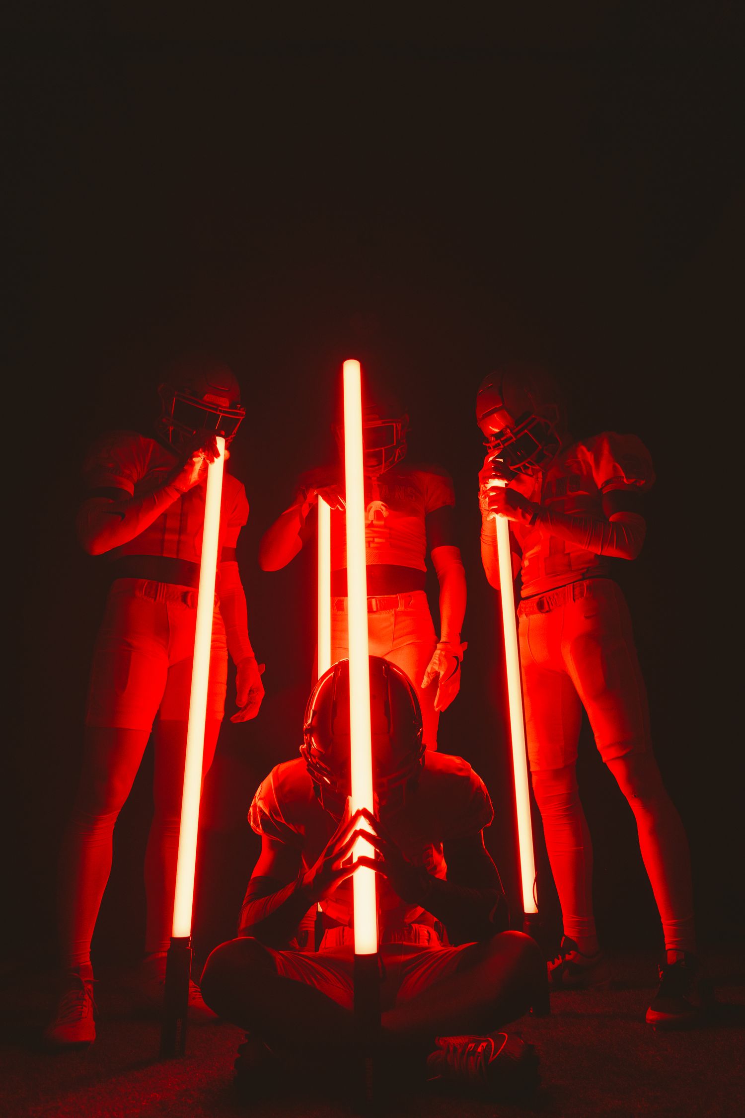Art installation featuring people posing with glowing red light bars in darkness.