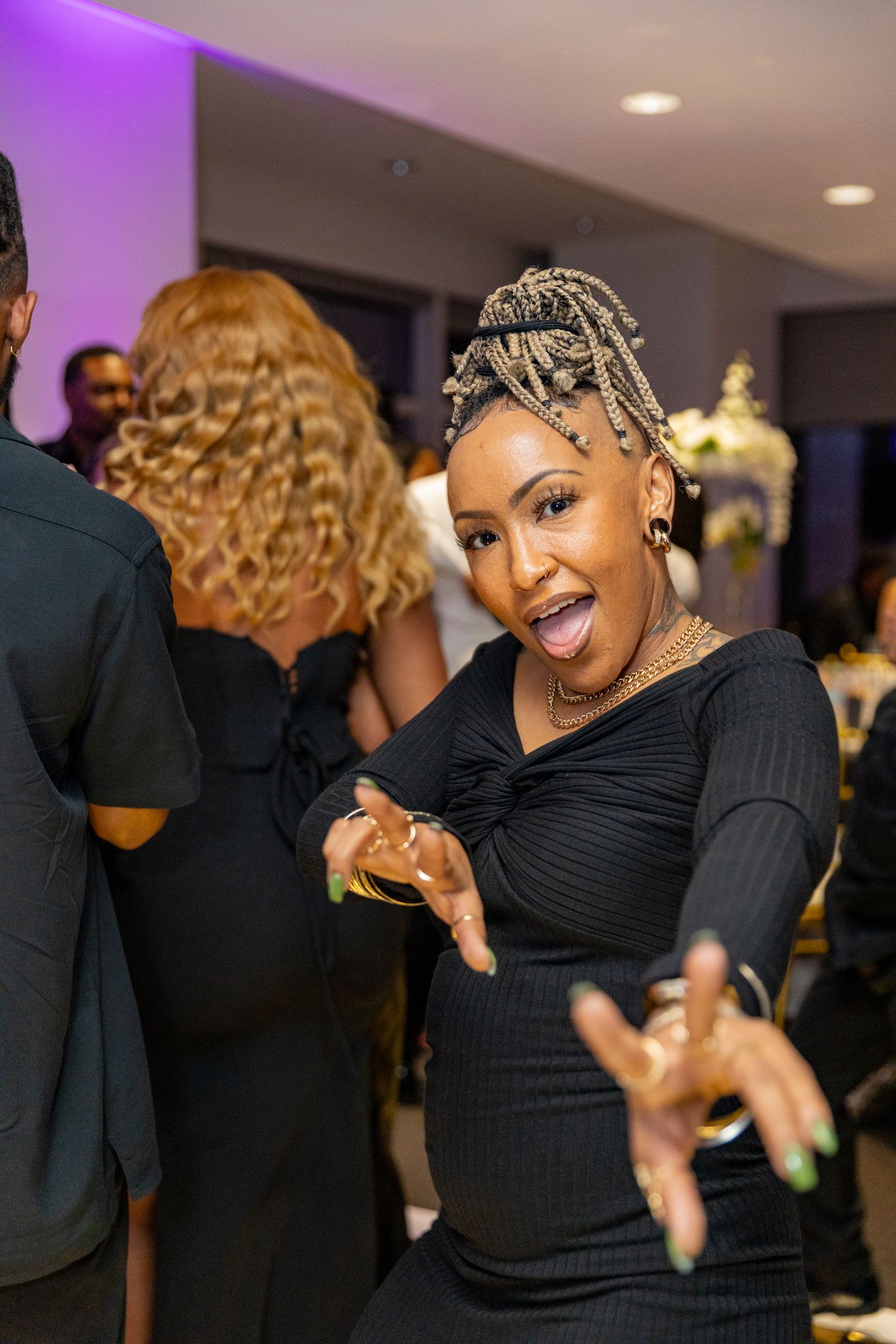 Woman in black dress dancing and having fun at an indoor party with purple lighting.