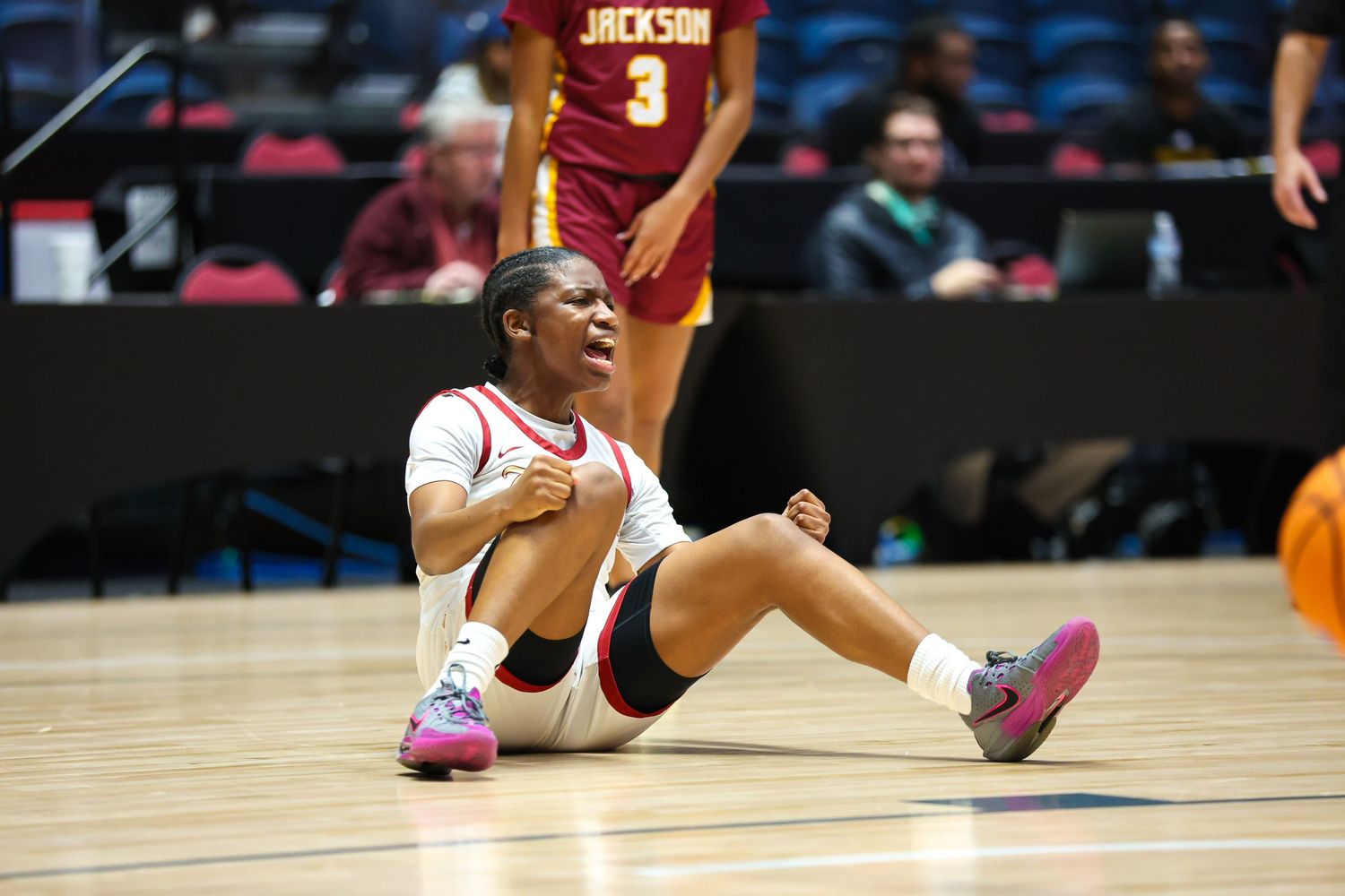Basketball player falling on court during intense game action.
