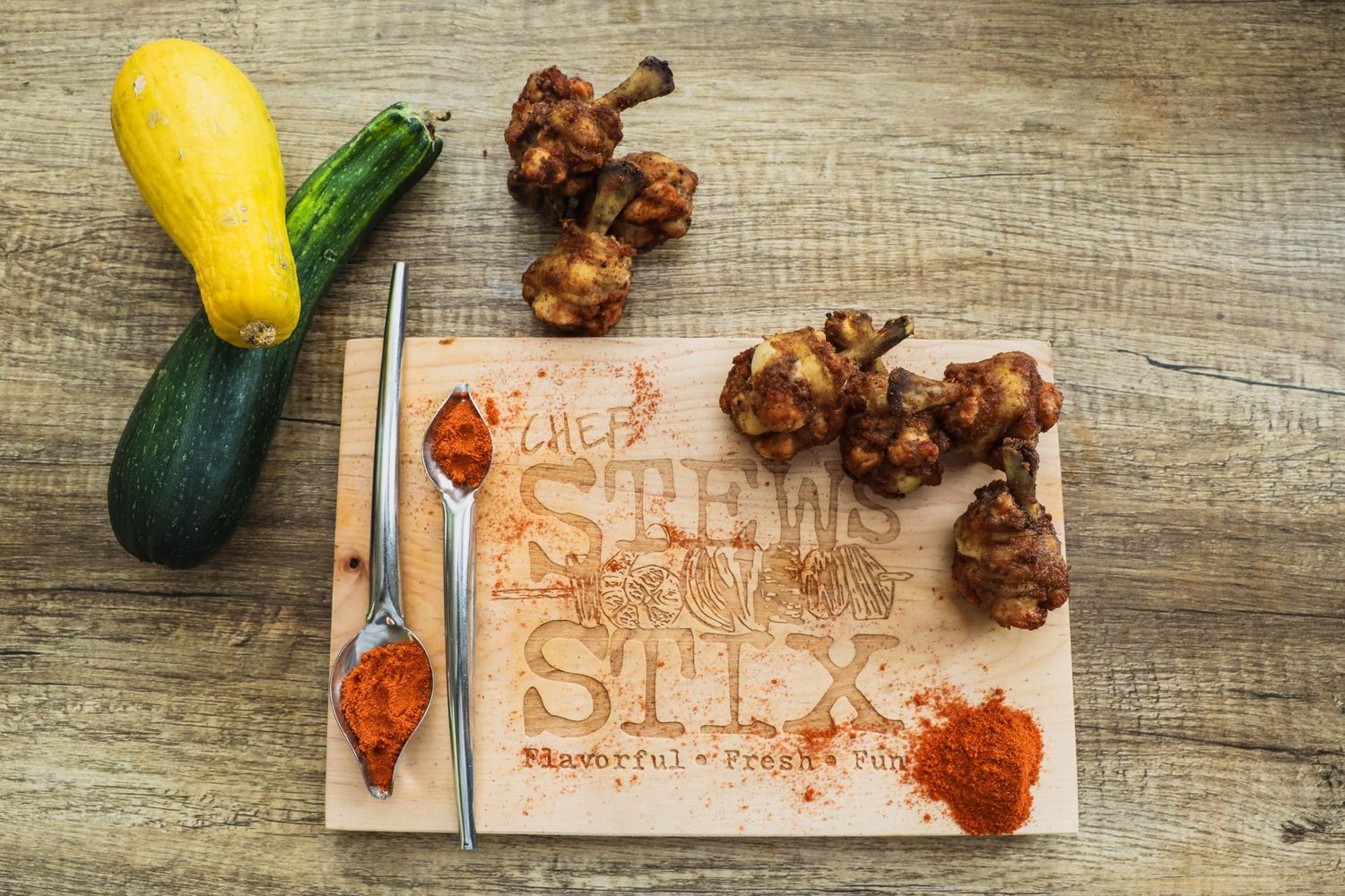 Food platter with chicken wings, squash, and zucchini on wooden surface.