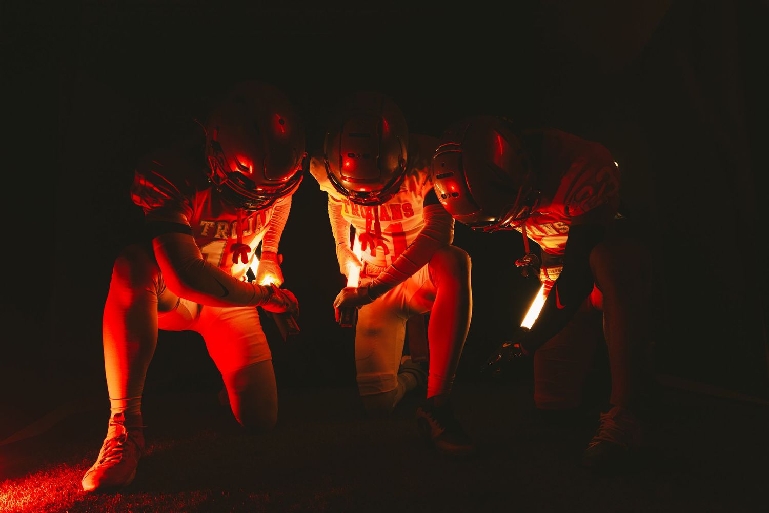 Group of athletes in dramatic red lighting creating shadowy silhouettes.