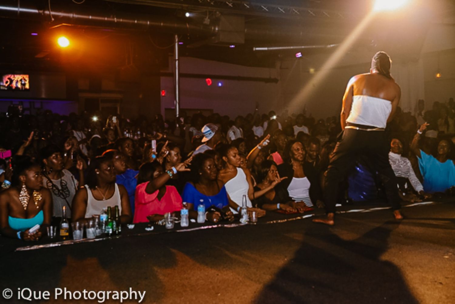 Crowd watches performer on stage at nightclub event.