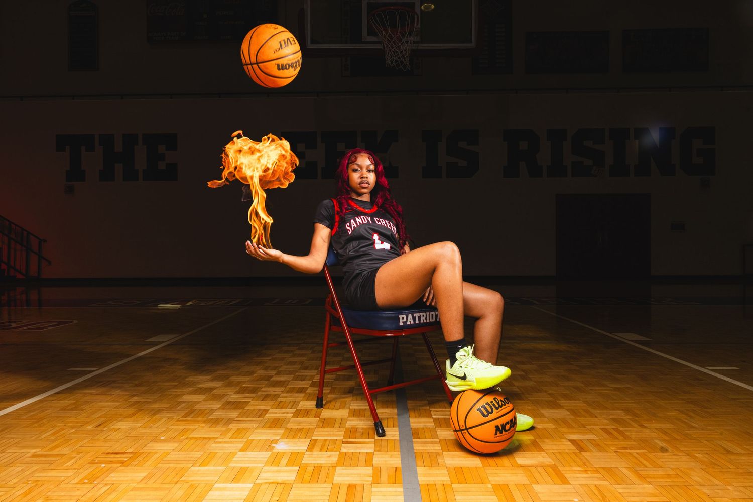 Basketball player sits on court chair with flaming basketball and dramatic lighting.