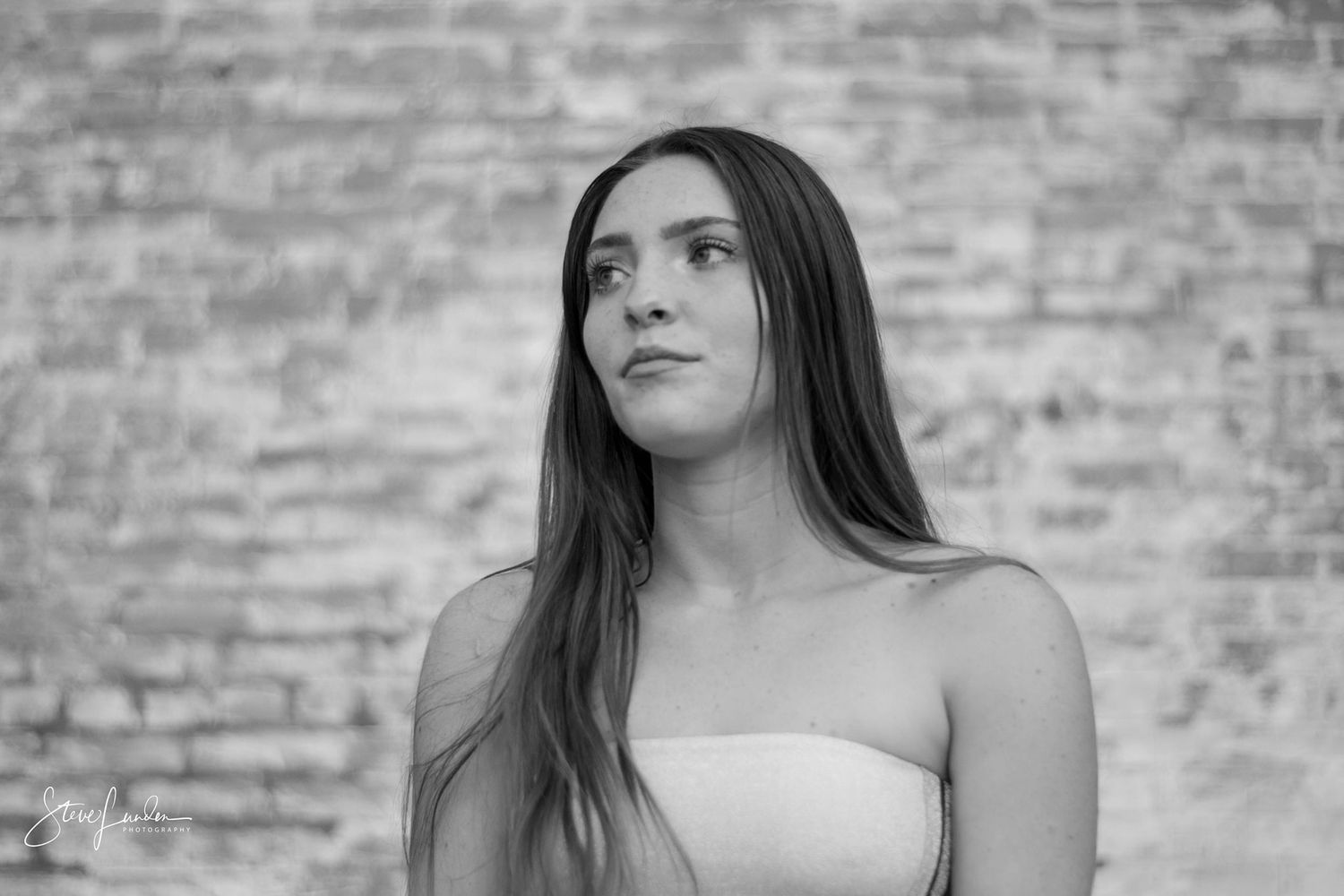 younf woman posing in front of brick wall