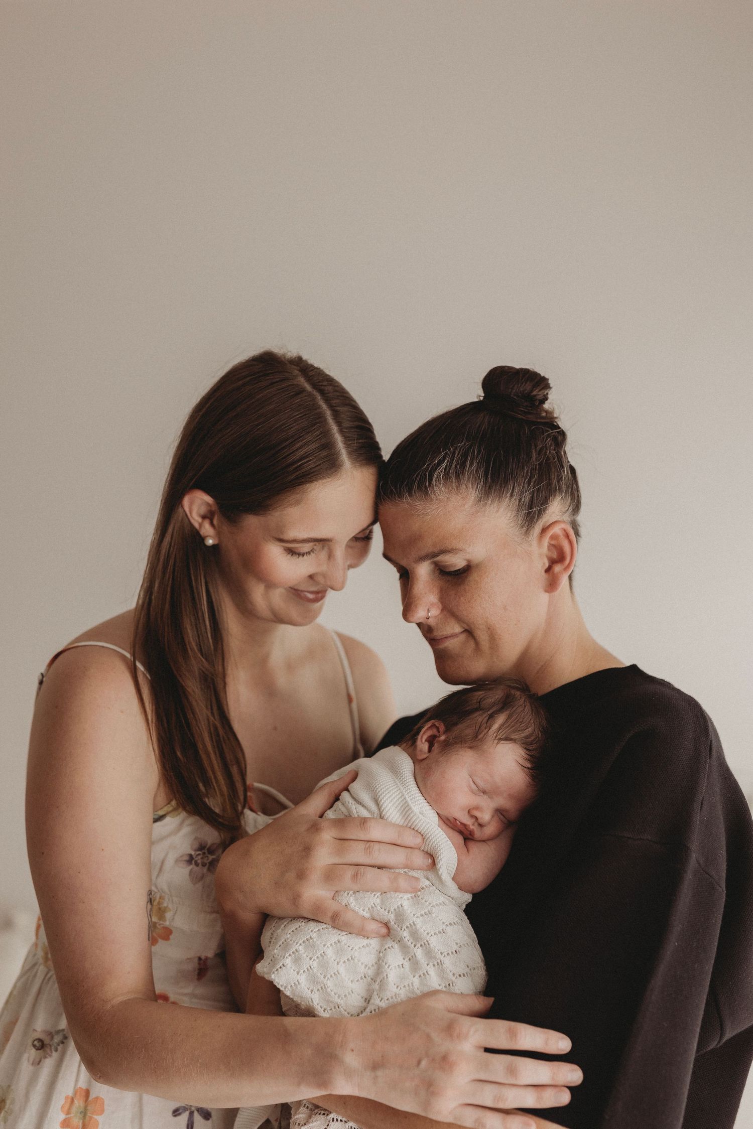 two mums with their newborn baby boy cuddled in warm geelong photographer studio