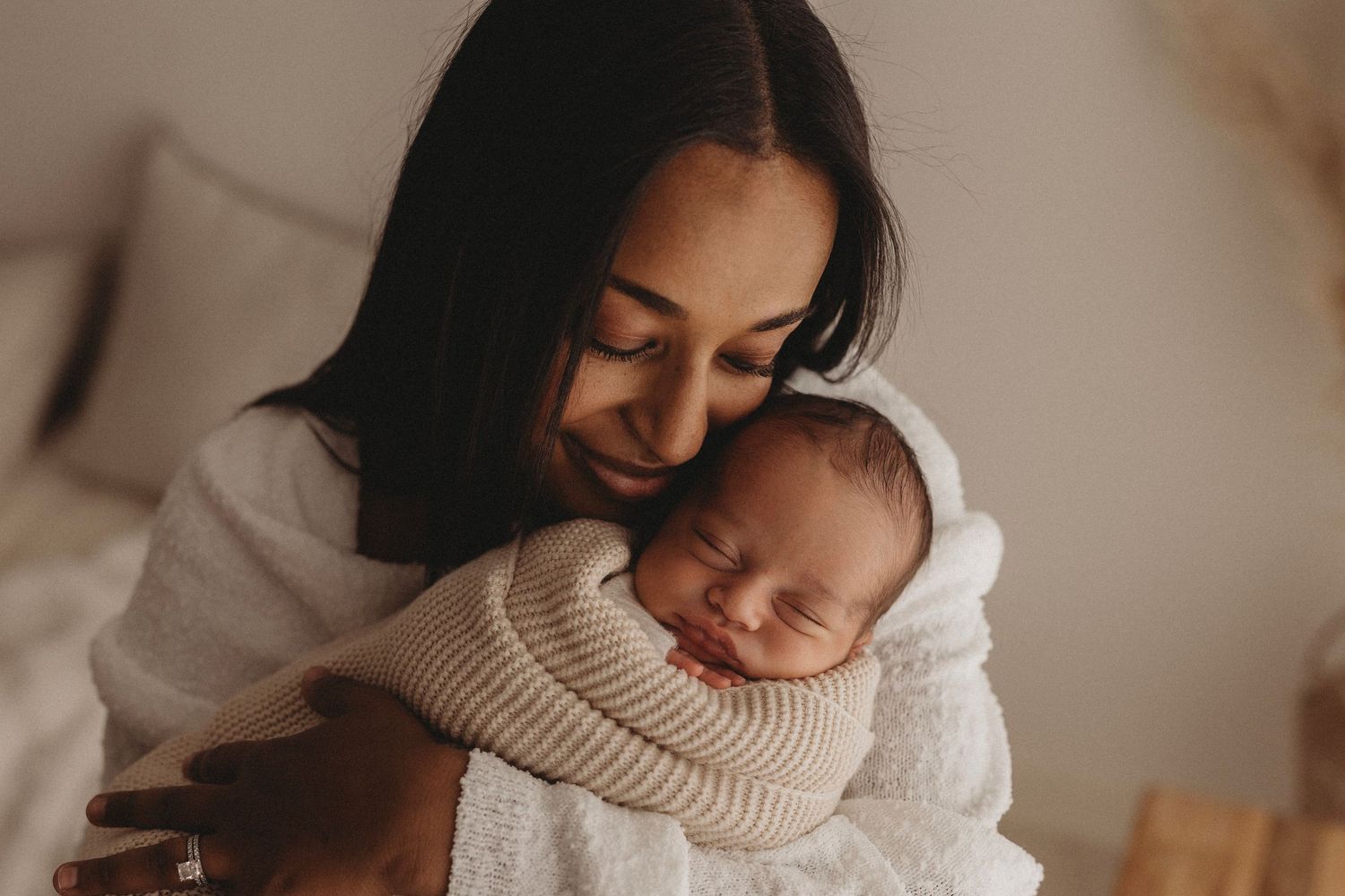 new mum holding newborn baby smiling baby sleeping wrapped in knit blanket in Geelong photographer studio