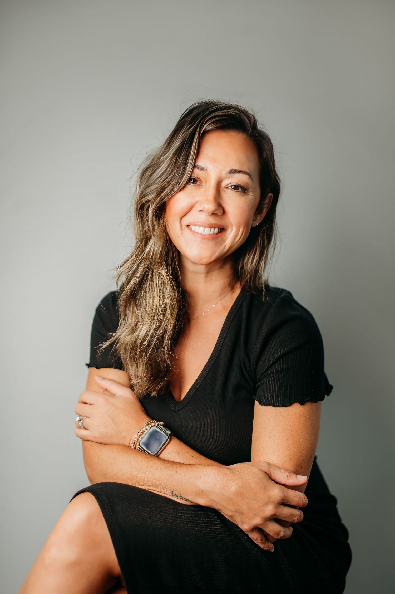 Professional studio portraits in black top showing casual poses against a grey backdrop.