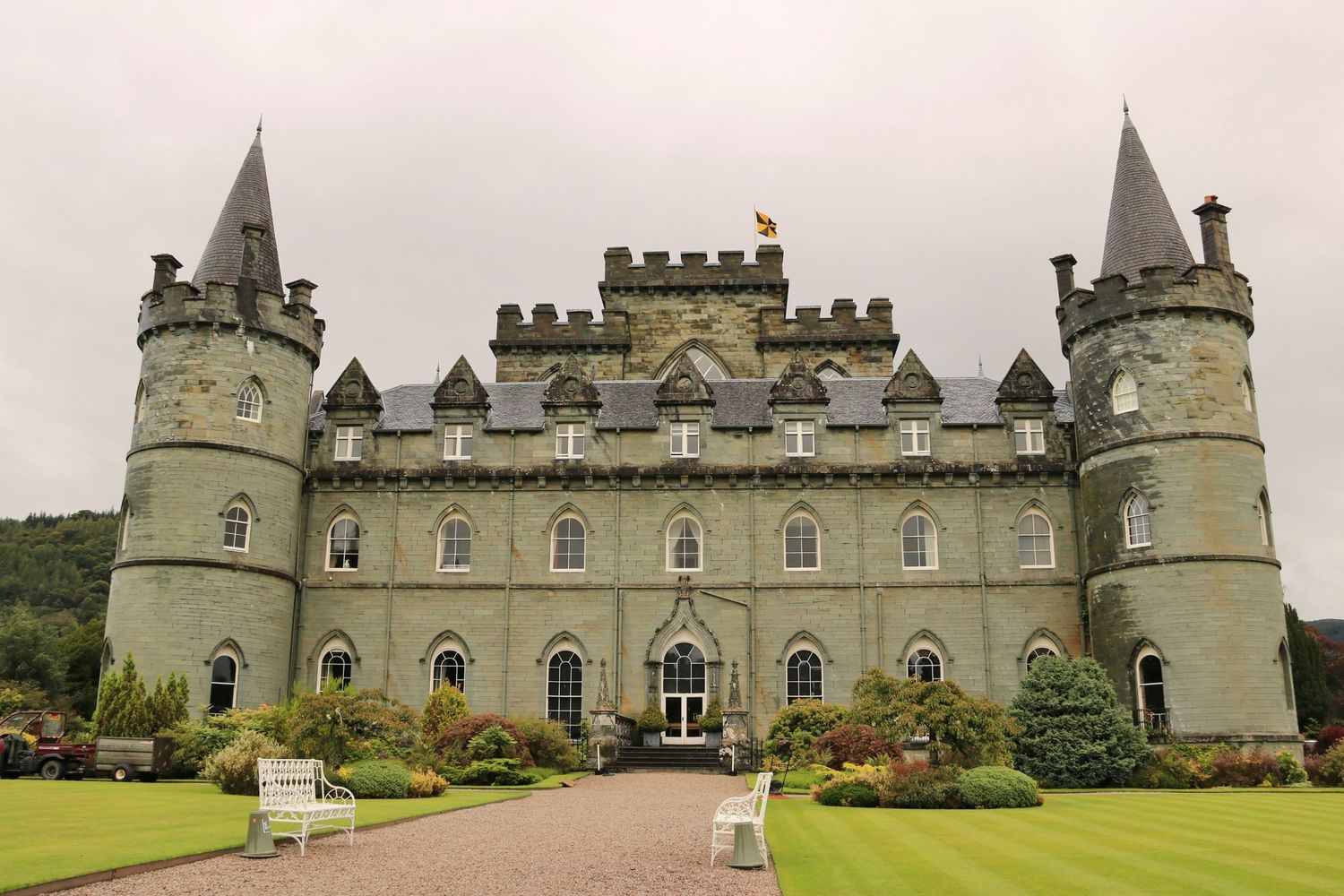 Inveraray Castle in Scotland features Gothic architecture with twin spires and manicured gardens in the foreground.