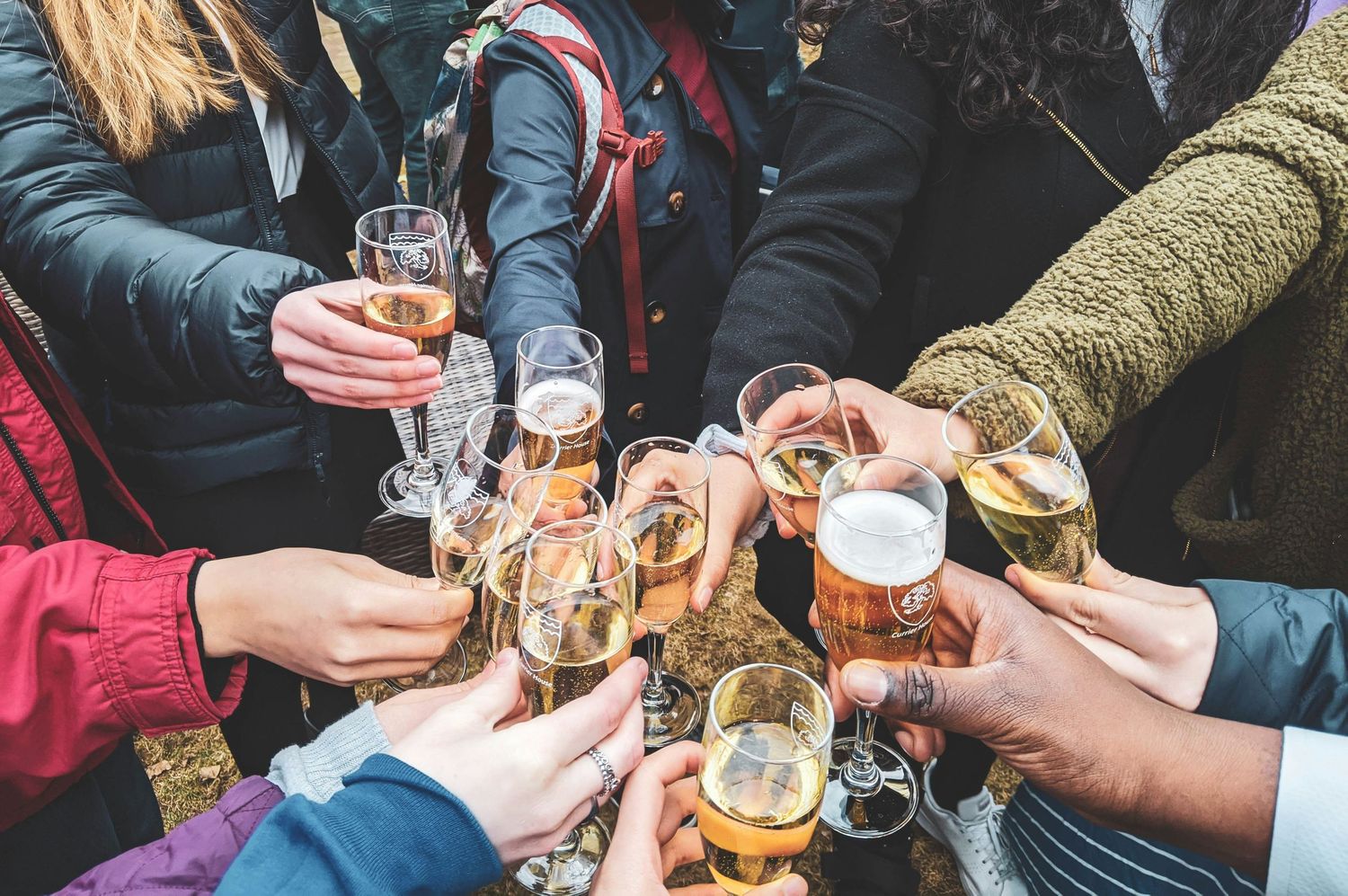 Close-up shot of hands passing beer glasses and toasting during a social gathering outdoors.