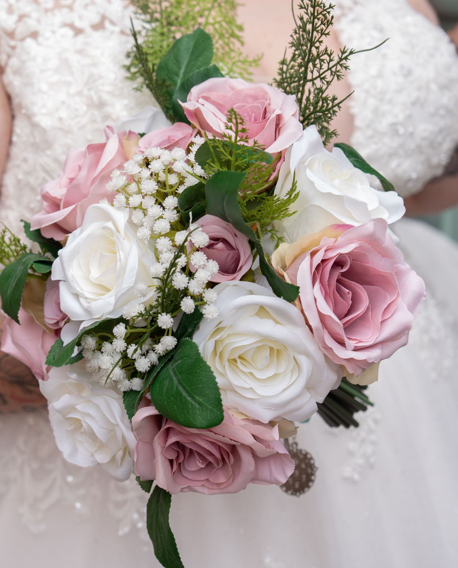 Delicate pink and white rose bouquet with baby's breath and greenery details for a wedding celebration.