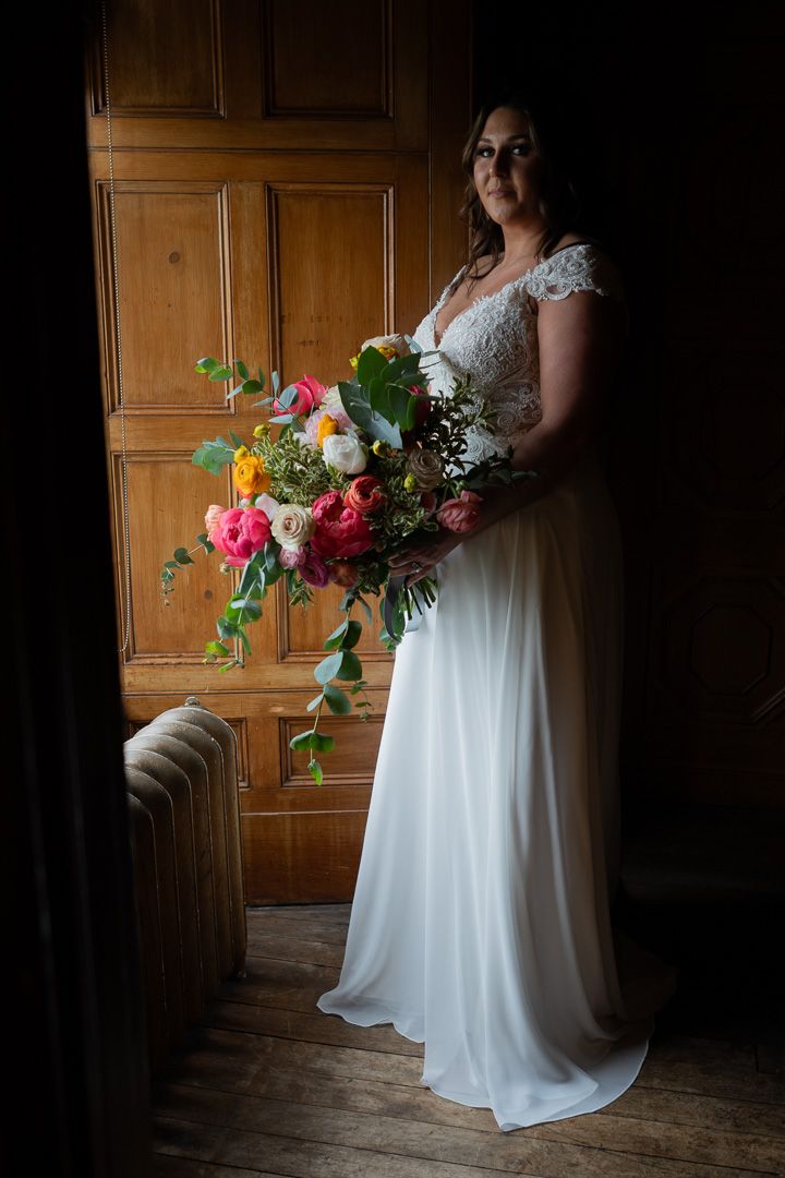 Artistic bridal photos showing flowing white gown and vibrant floral bouquet against wooden paneled walls.