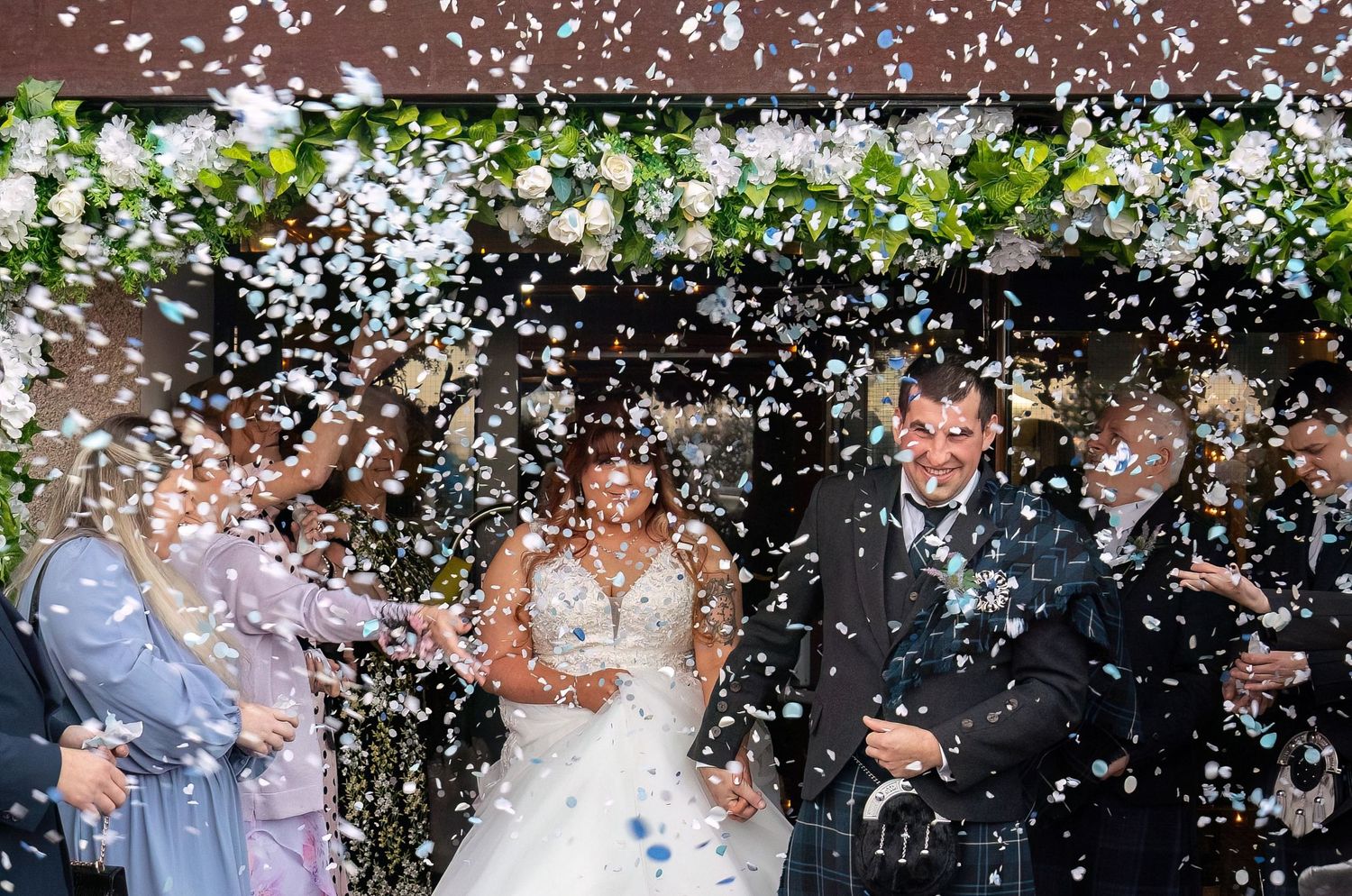 Confetti rains down on wedding guests during outdoor celebration.