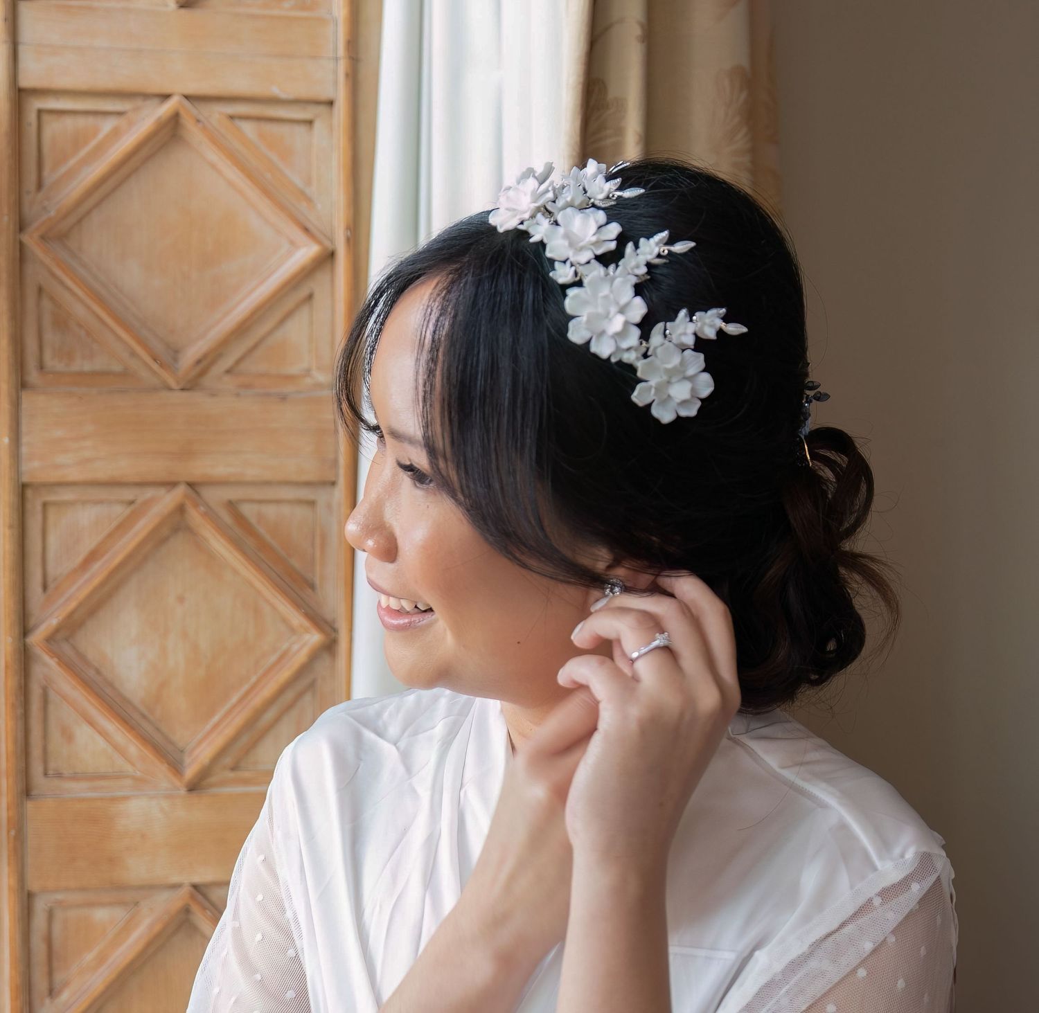Side view of someone wearing a delicate floral lace hair accessory and white dress in soft natural light.