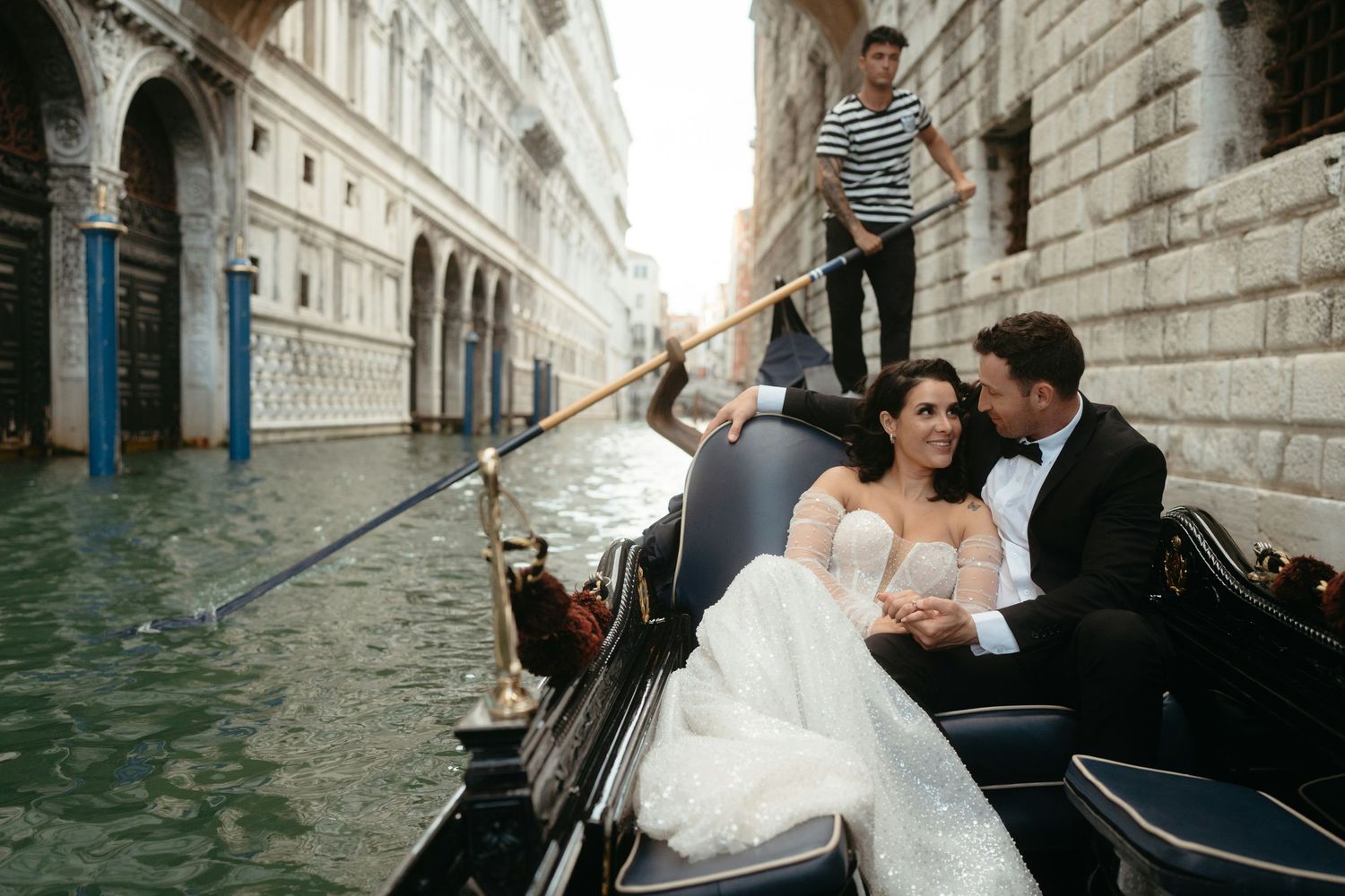 A couple shares an intimate moment while riding in a gondola through the scenic canals of Venice, Italy.