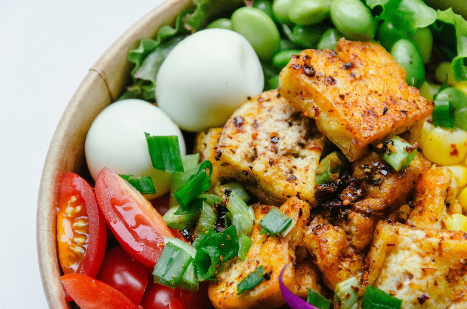 A vibrant bowl of curried cauliflower with fresh vegetables and herbs arranged in a colorful medley.