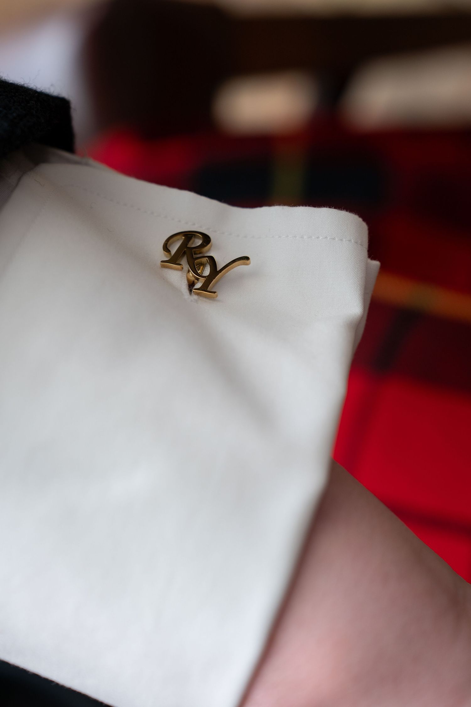 A gold ring with a subtle curved design sits delicately against a white surface.
