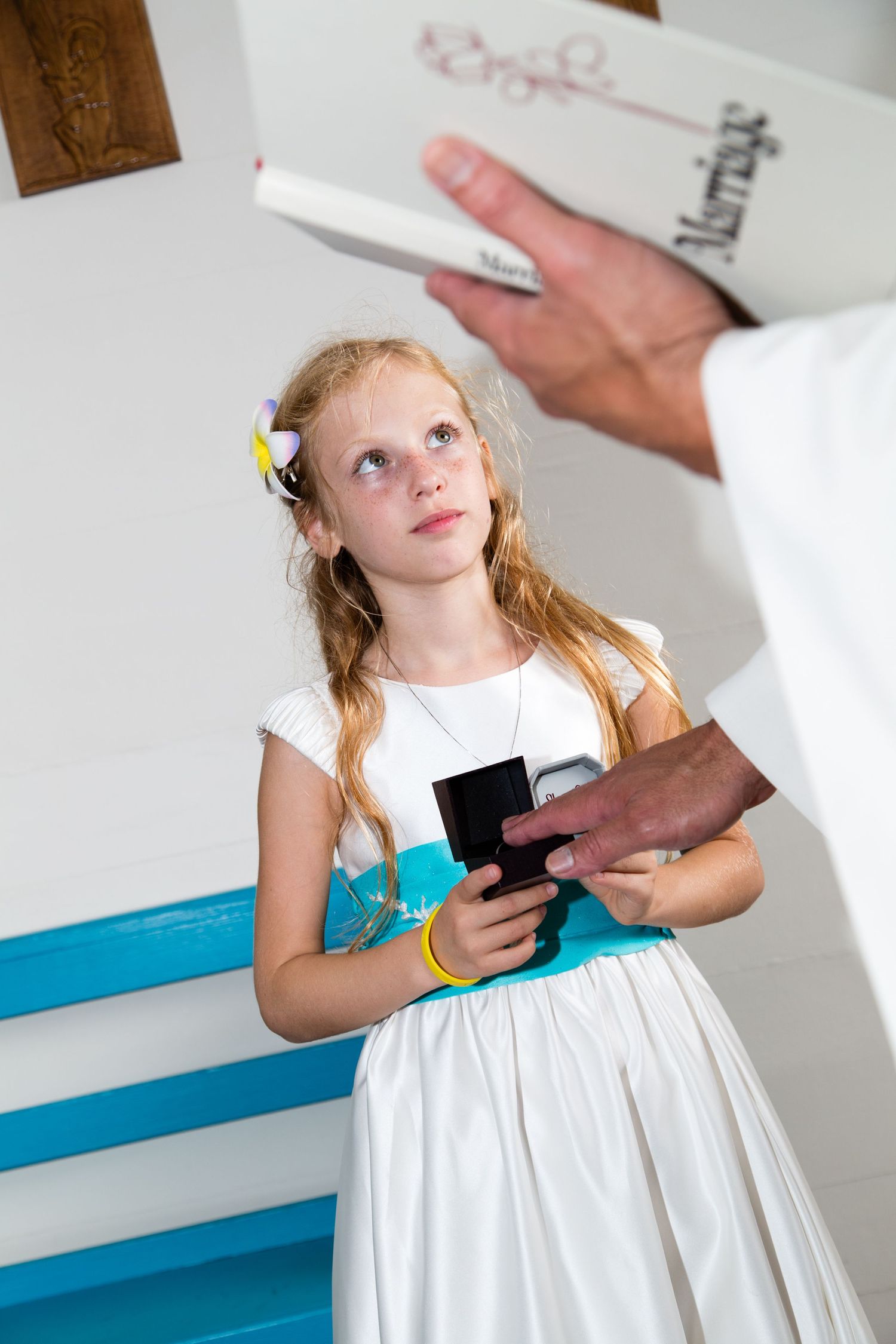 Young girl in white dress looking up during formal ceremony moment at the Saint Peter's church of Kailua Kona, Hawaii.