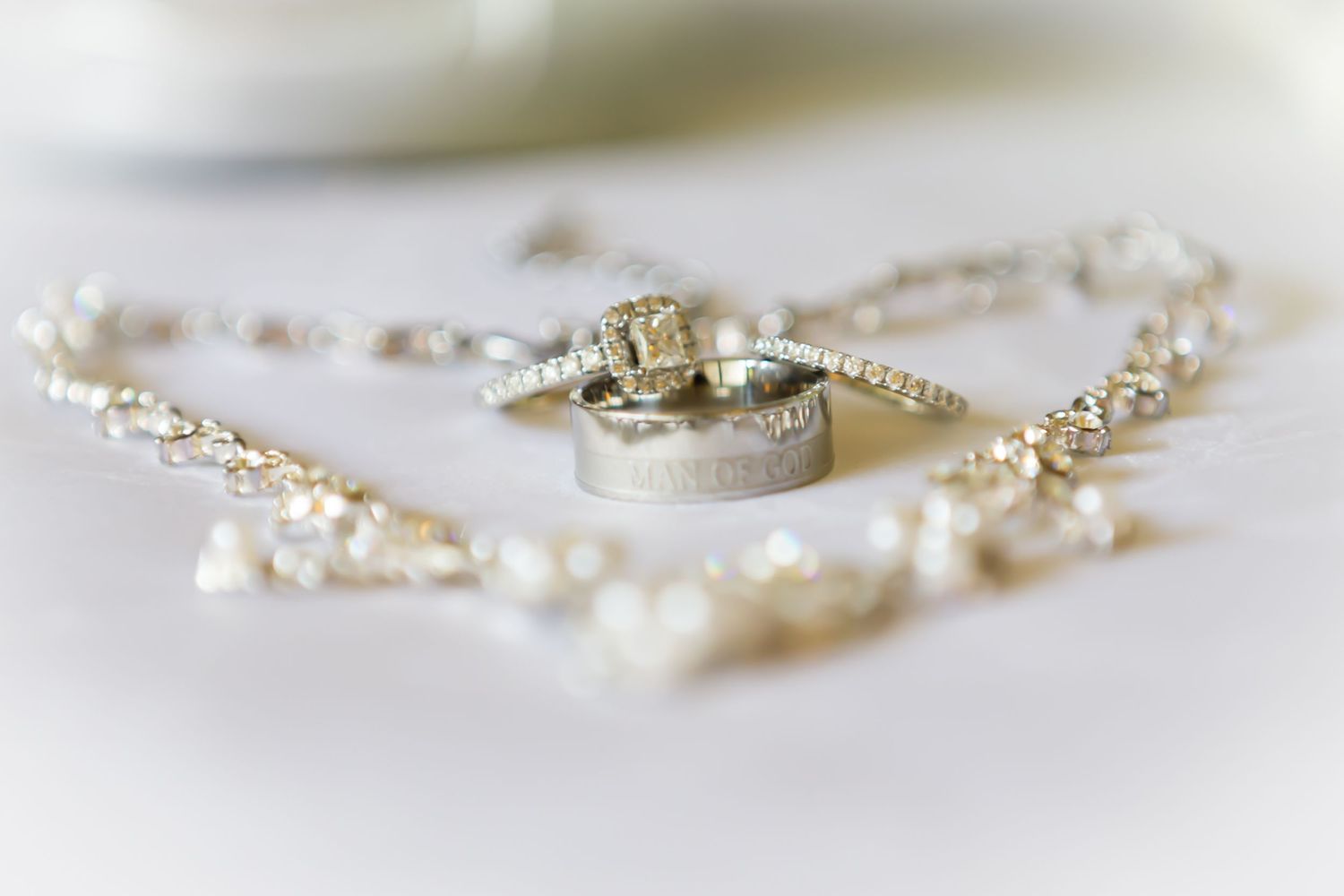 Wedding rings arranged inside delicate pearl heart on white background.