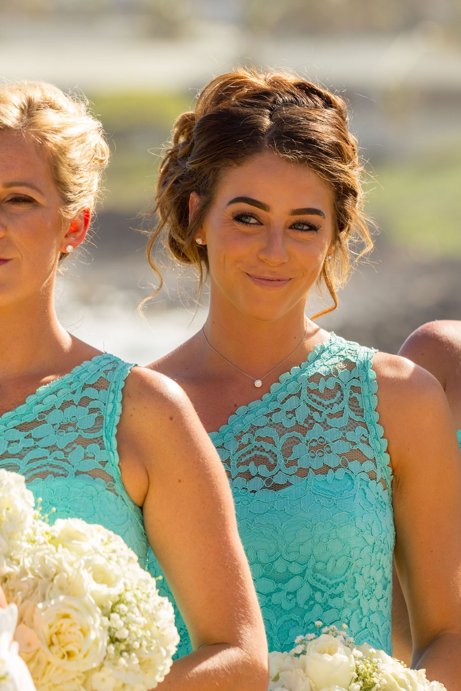 Bridesmaids in matching turquoise lace dresses holding white bouquets at a wedding in Kauai.