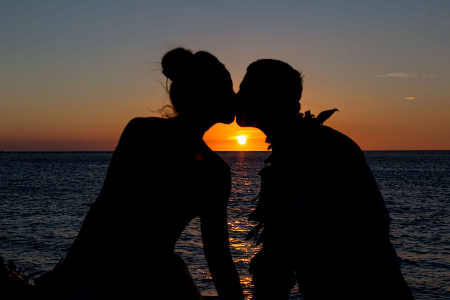 A silhouette of a couple kissing against the sunset in Kailua Kona, Hawaii.