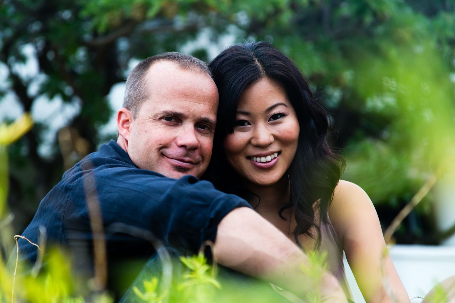 Intimate portrait of a couple sharing a happy moment in a garden setting during an engagement photography session in Kailua Kona, Hawaii.