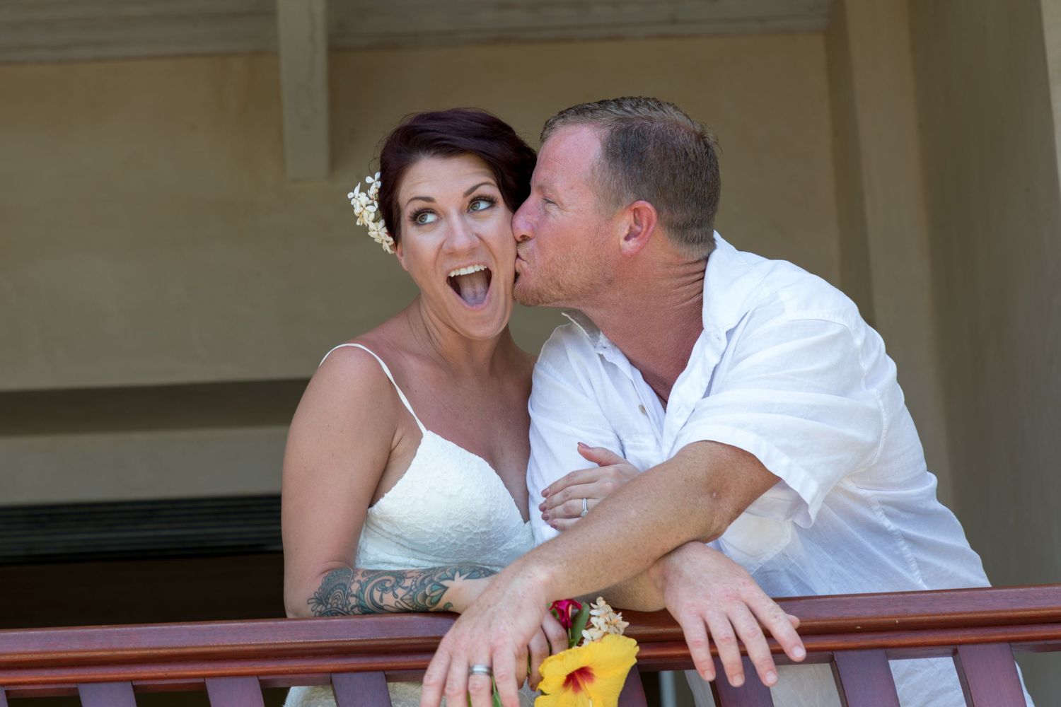Playful wedding moment captured on balcony in casual white attire at a private state in Kona, Hawaii.