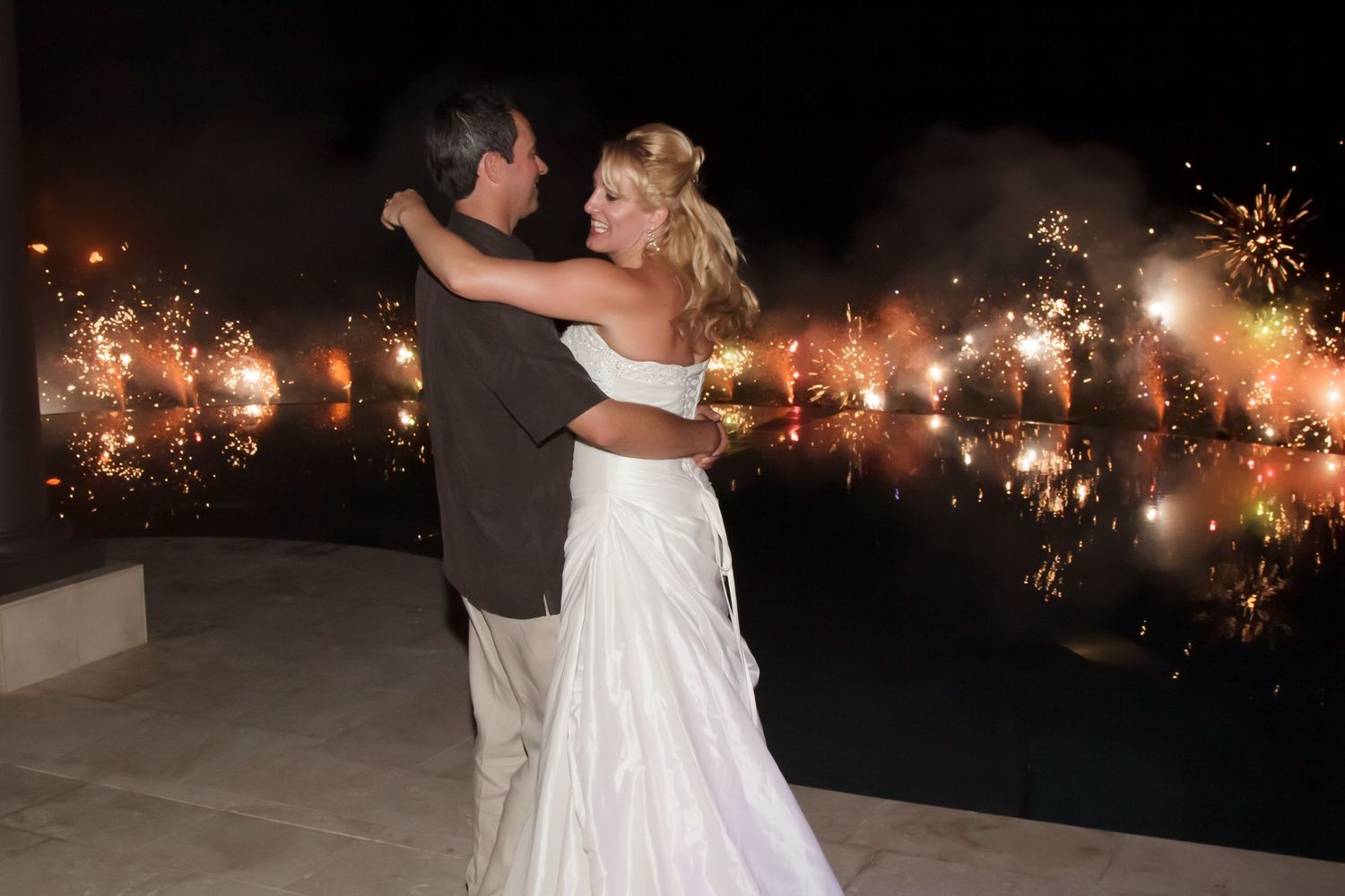 A couple shares their first dance with sparklers, creating a magical nighttime backdrop at a wedding on a private state in Kailua Kona.