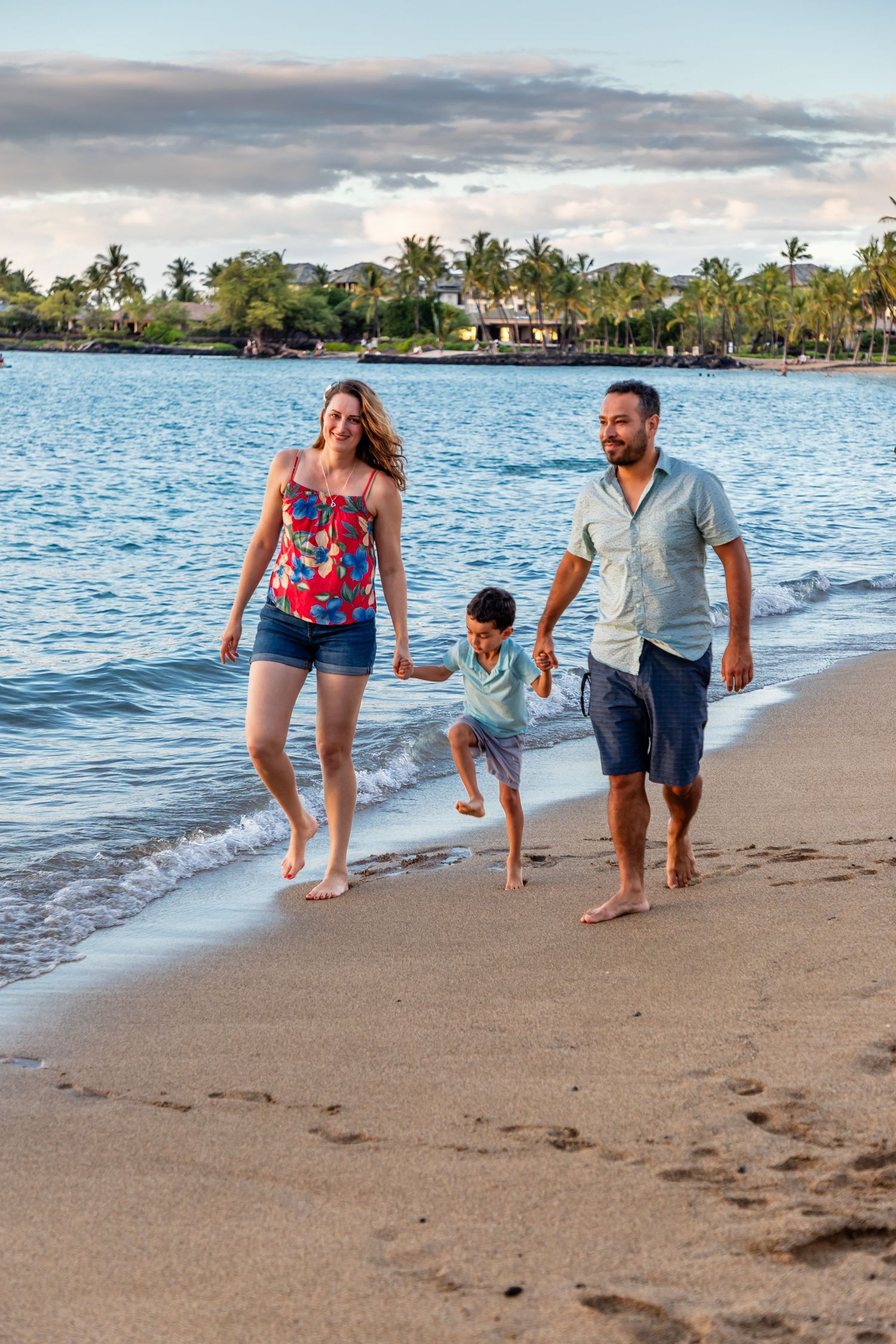 The photographer captured this beautiful portrait of a happy family walking together along the shore on a beach near Kailua Kona, Hawaii.