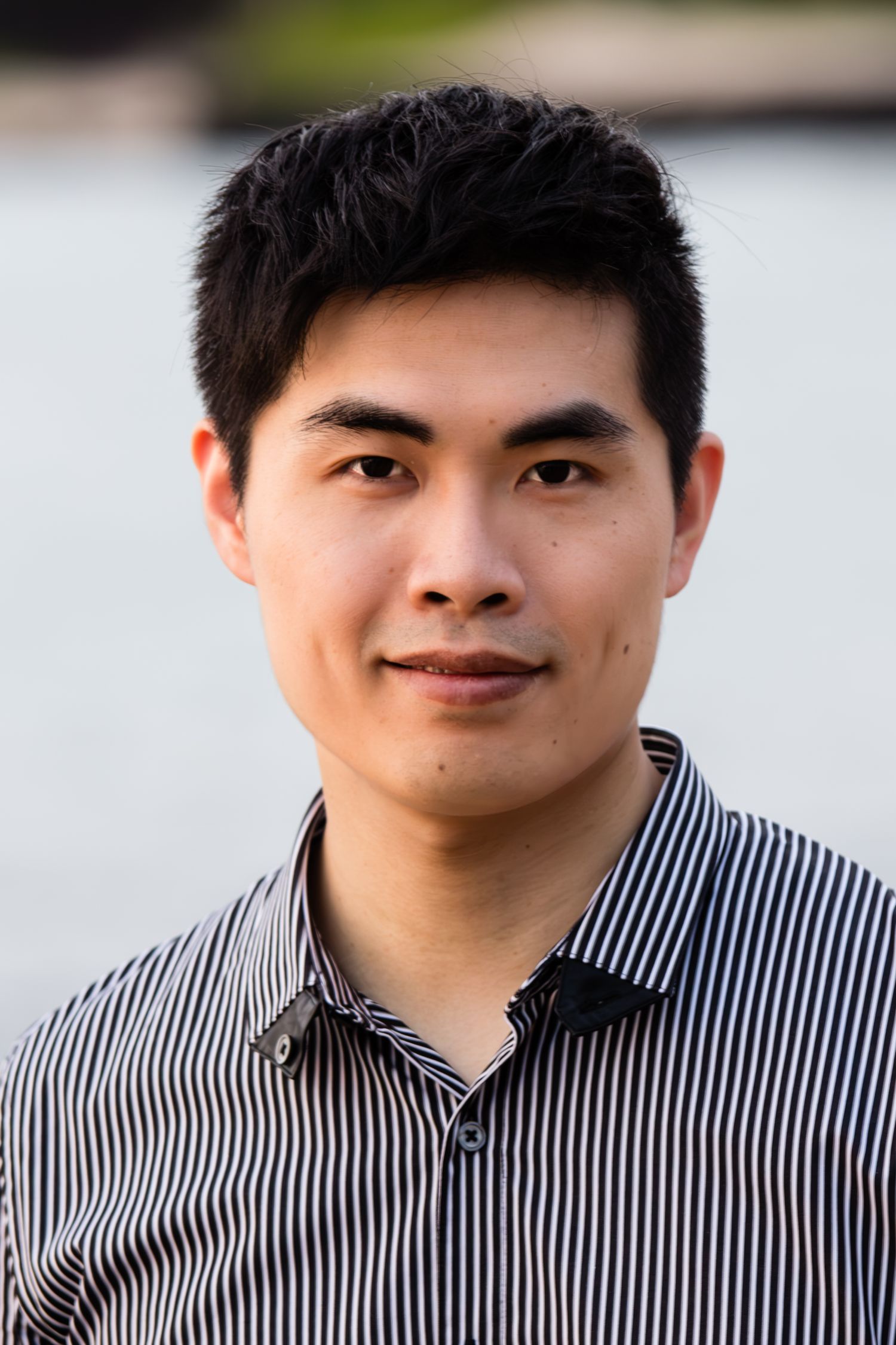 Professional headshot of an Korean man in a striped shirt against a blurred background at Anaehoomalu Bay beach in the Big Island of Hawaii.