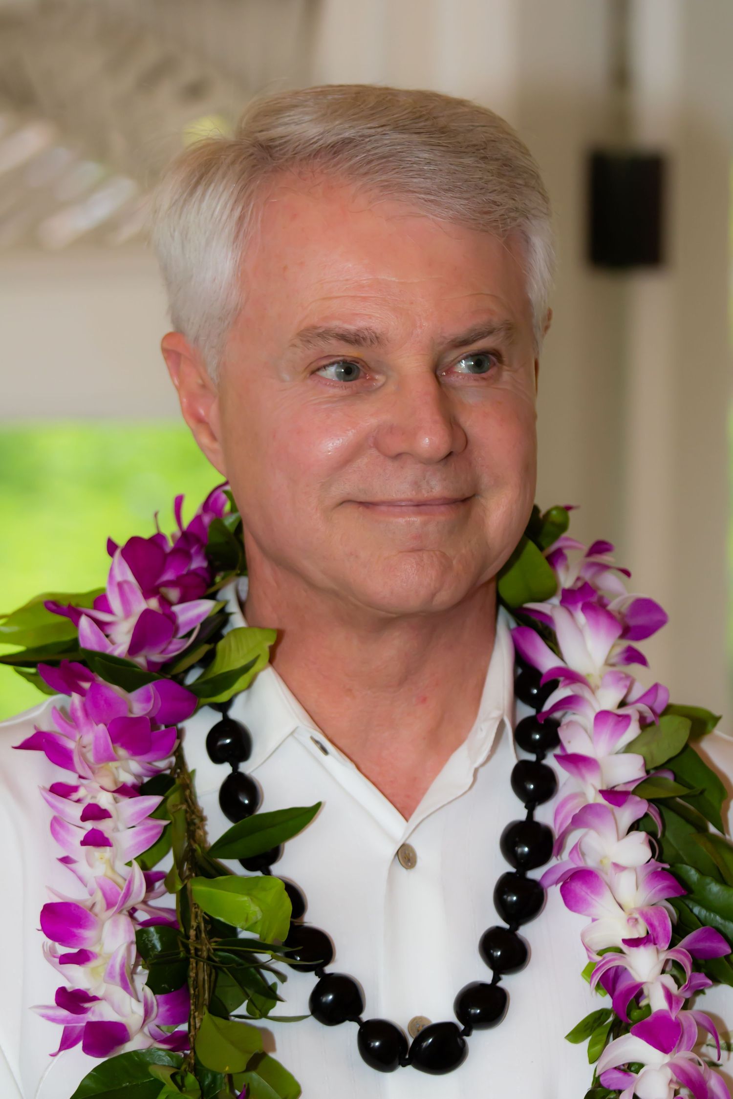 Portrait of a groom with a traditional Hawaiian lei of purple orchids, during a same sex wedding celebration at the Hilton Waikoloa Village.