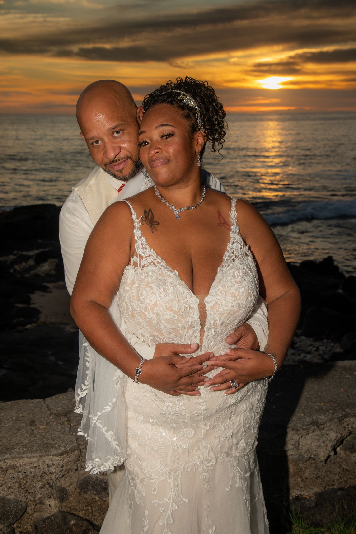 A romantic sunset wedding photo on a beach with dramatic orange sky and ocean backdrop in a wedding at Papa Kona,