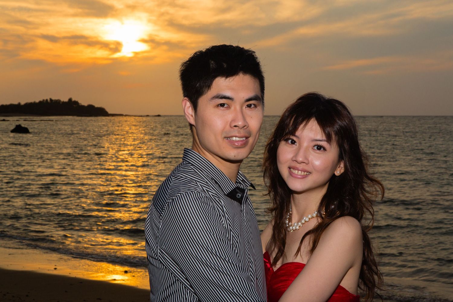 A couple poses for a portrait at sunset during an engagement session by the ocean at Anaehoomalu Bay beach near Kailua Kona.