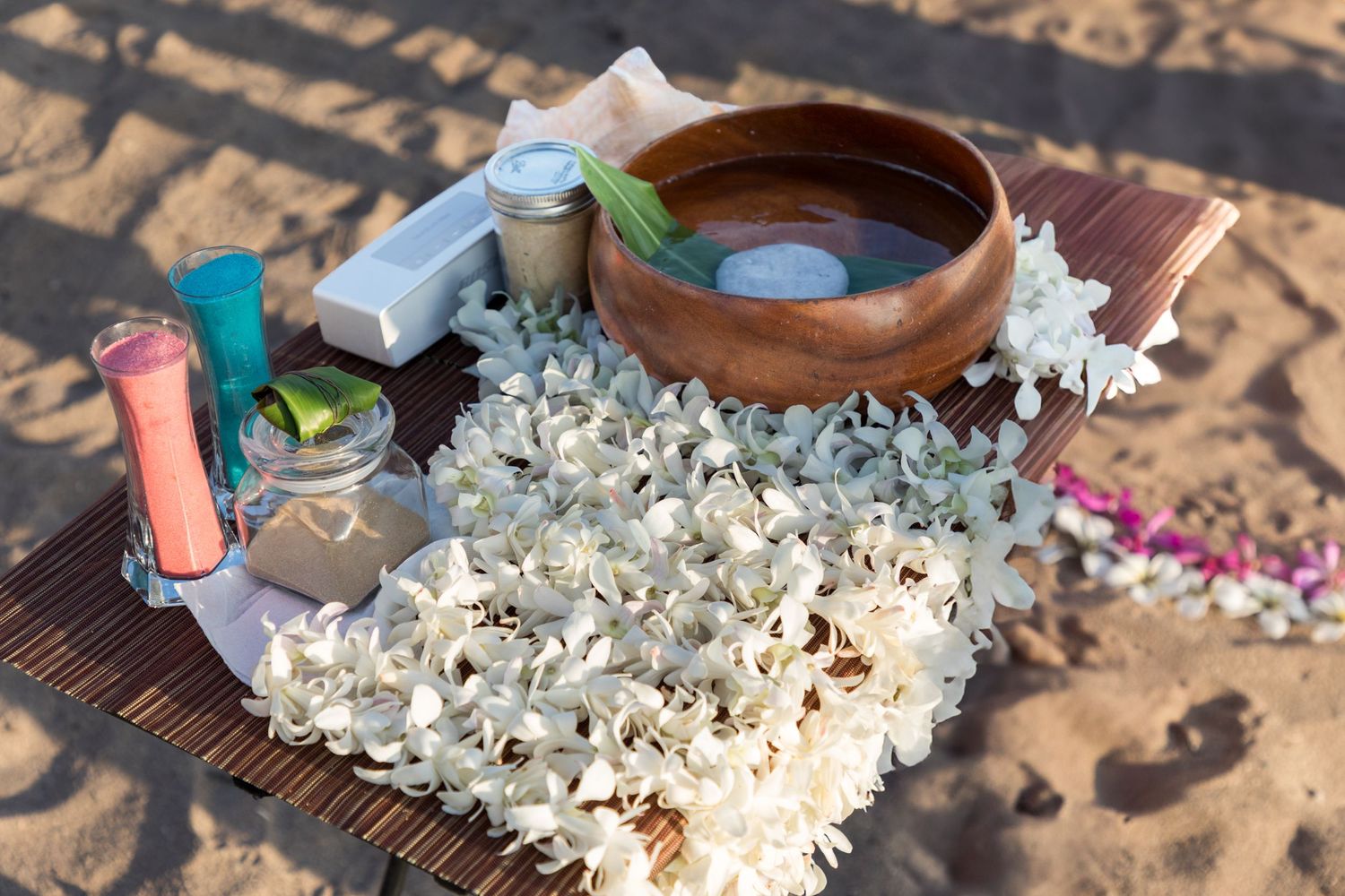 Hawaiian wedding ceremony setup with floating candles and white plumeria leis at Kukio beach in Kailua Kona.