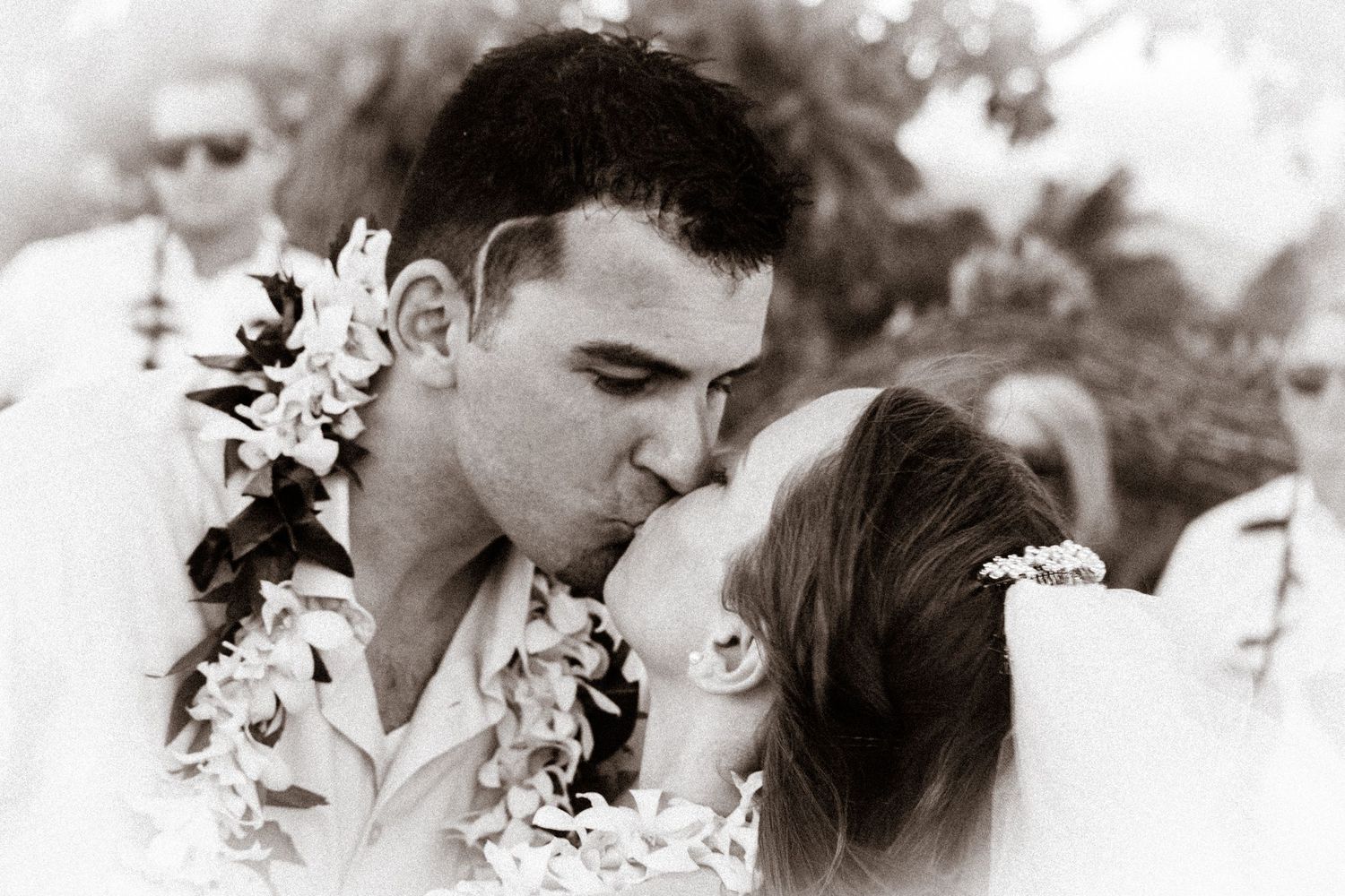 A romantic black and white wedding photo with traditional Hawaiian leis.