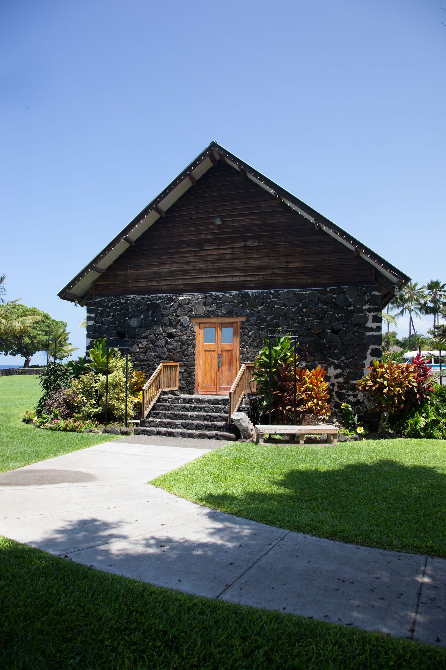 Living Stones historical church chapel rock and wood building with orange flowers and green landscaping.