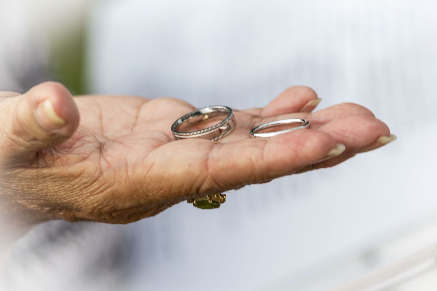 Two wedding rings held in an open palm against a white background at a Kailua Kona, Hawaii wedding.