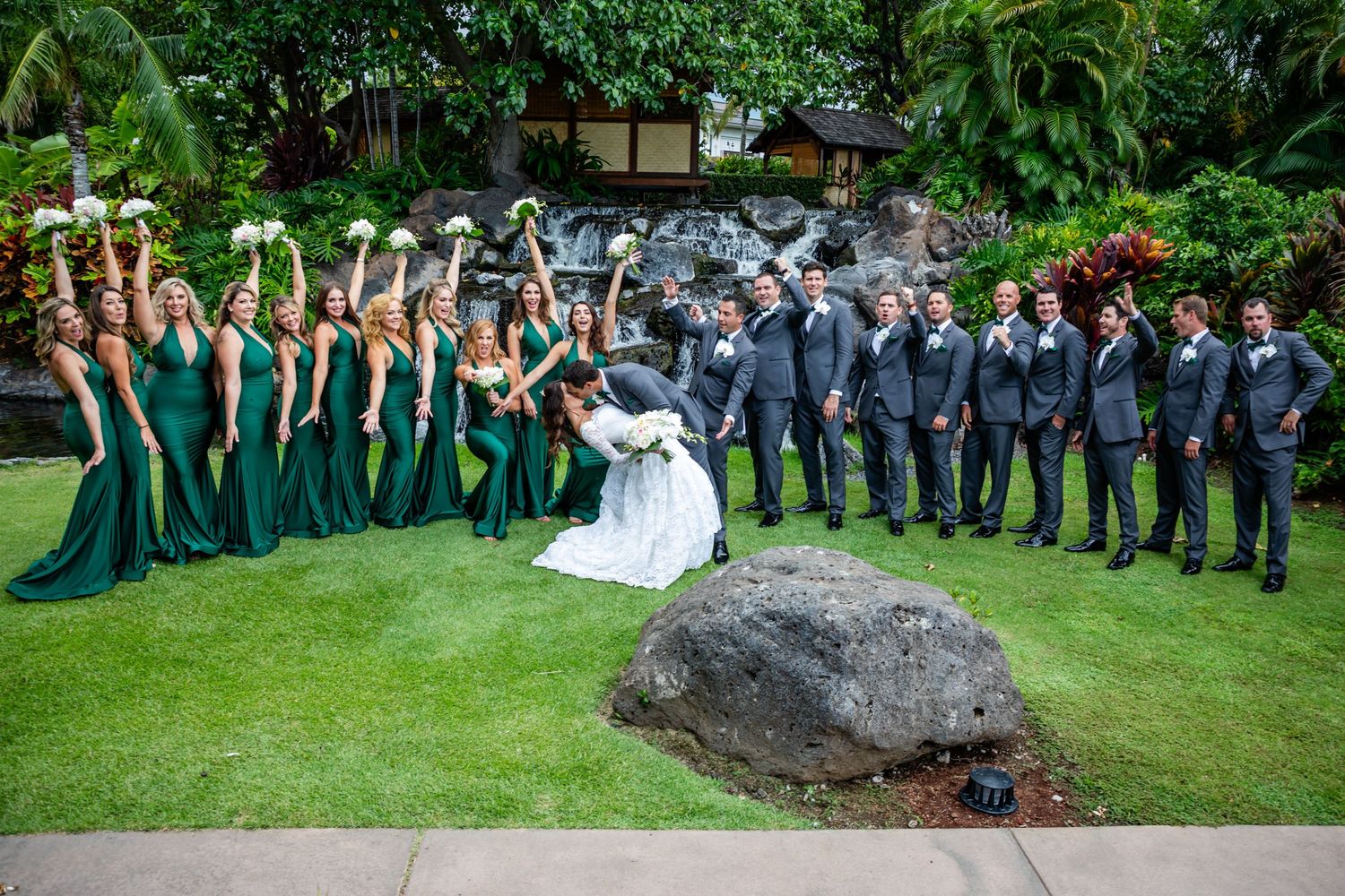 Wedding party in green dresses and navy suits forms a stylish V-formation on the lawn of the Fairmont Orchid at Mauna Lani near Kailua Kona.