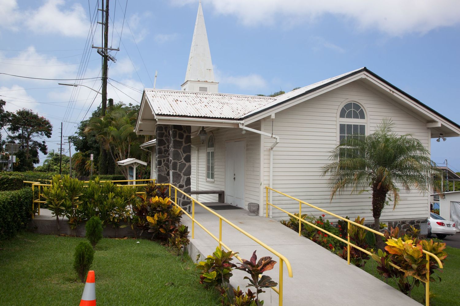 Small white church building with wheelchair ramp and tropical landscaping in Hawaii.