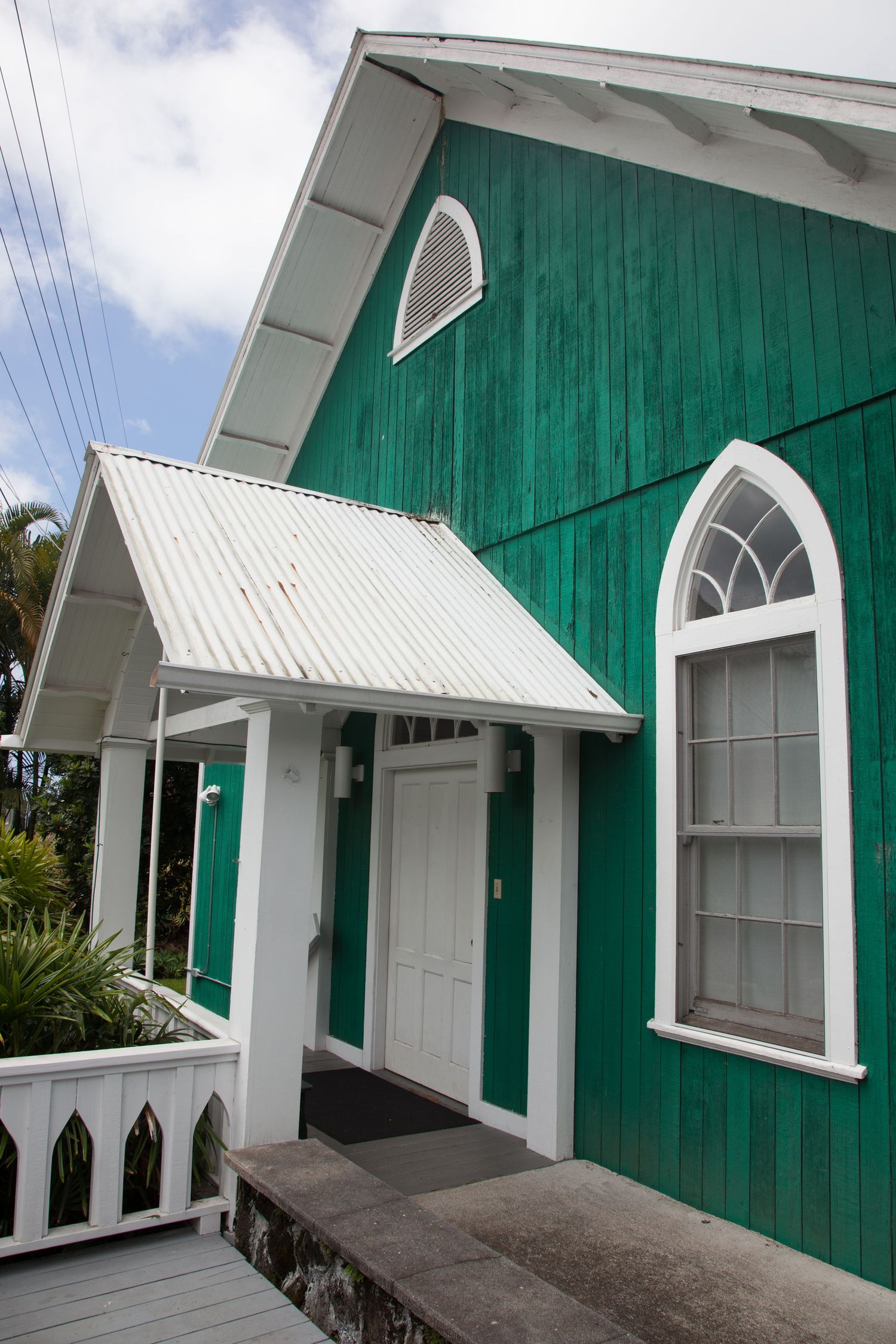 Bright green wooden chapel with white trim and arched windows in Hawaii.