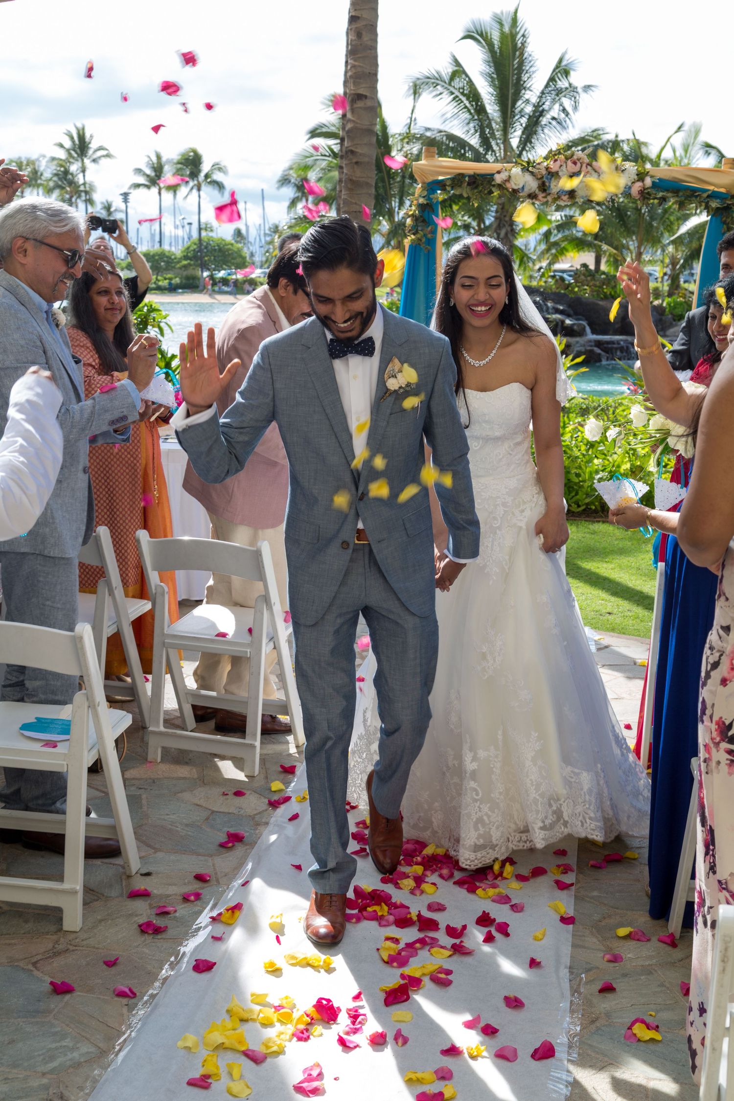 A couple exits their wedding ceremony under a shower of colorful flower petals at the Hilton Hawaiian Village in Honolulu, Hawaii.