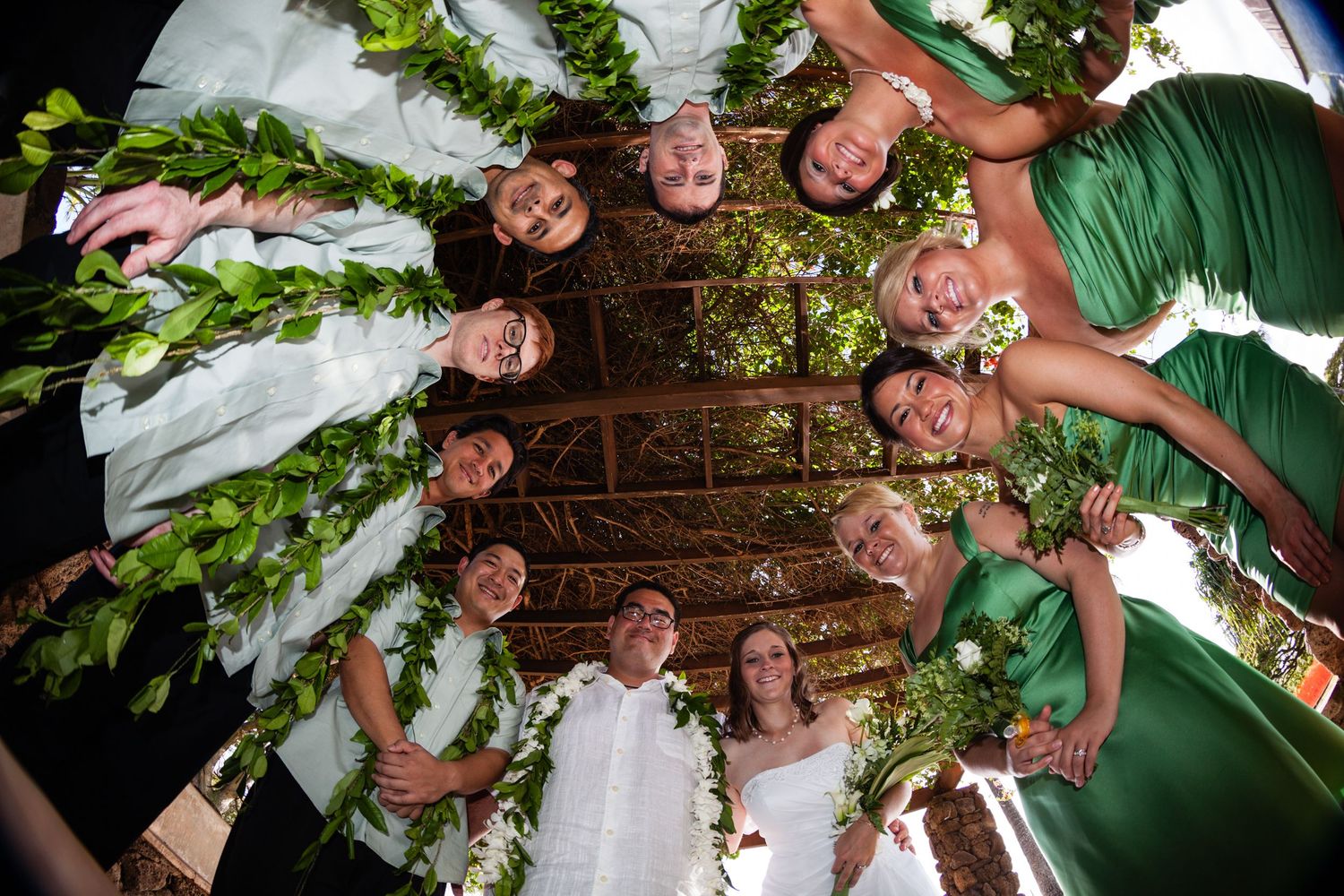 Wedding party creates circular formation with creative camera angle from below in a wedding on Honolulu, Oahu, Hawaii.