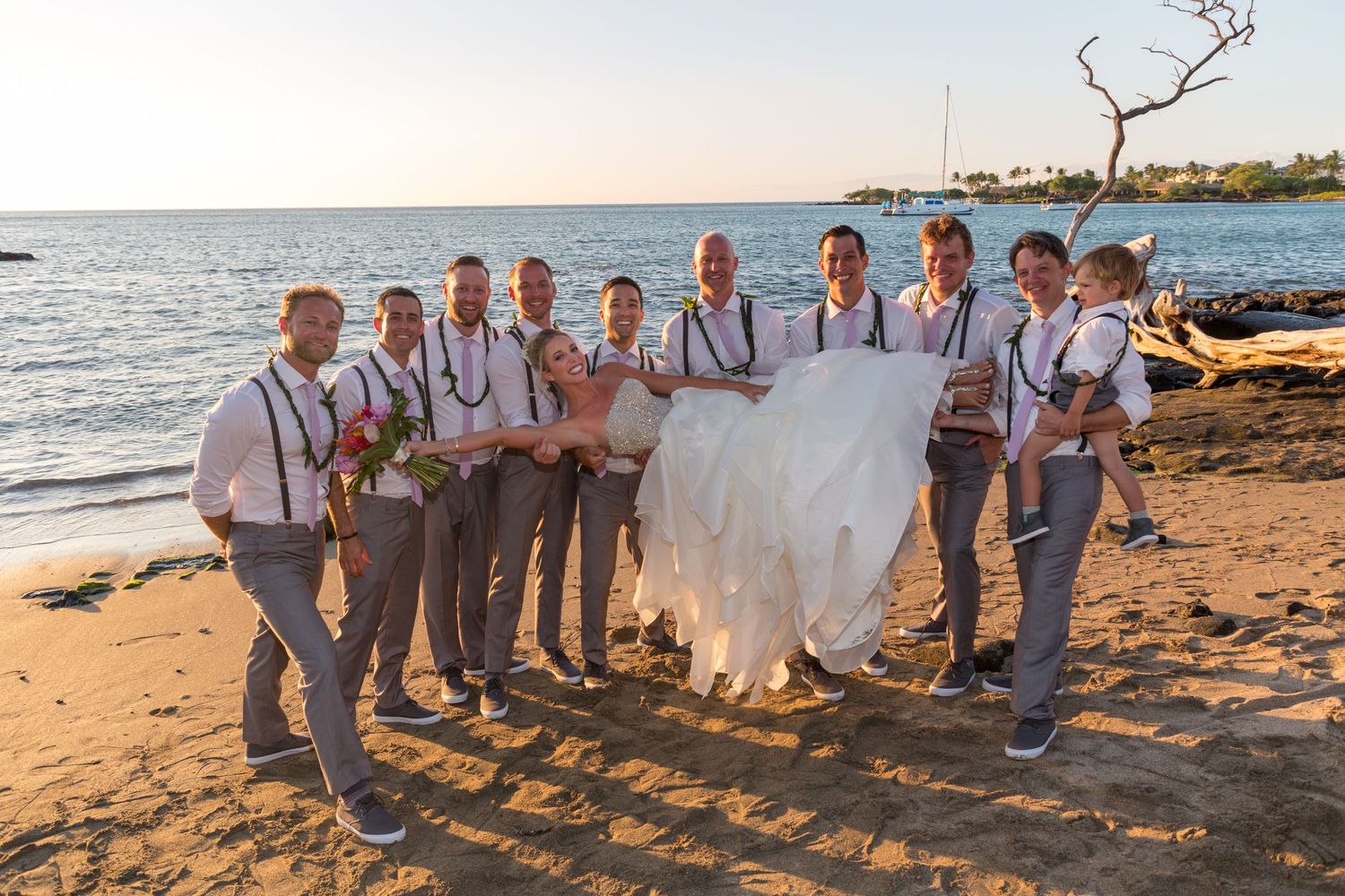 Wedding party walking along a sandy beach at sunset with long shadows stretching across the sand.